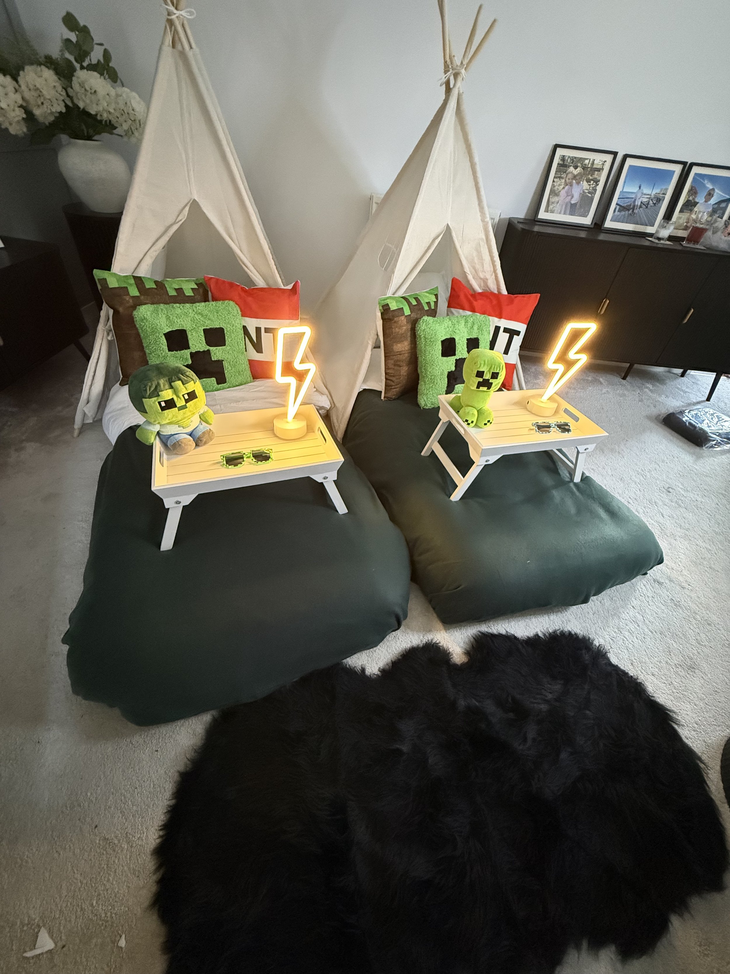 Minecraft Sleepover teepee party by Sweet Dreams Events showing two cream teepees with glowing lightning bolt neon lamps, Creeper face cushions, Minecraft plushies and dark green bedding for a boys birthday party in Surrey