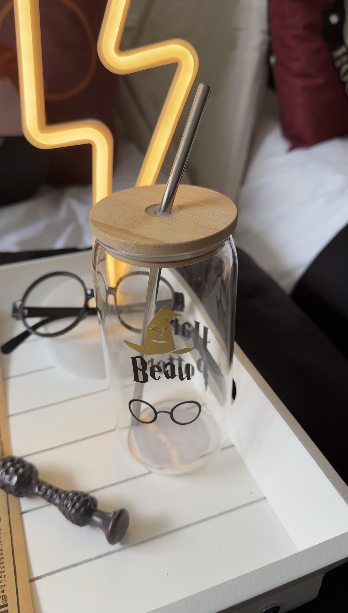 Personalised glass bottle with bamboo lid on a styled breakfast tray at a wizard themed sleepover, with round glasses and a warm neon light