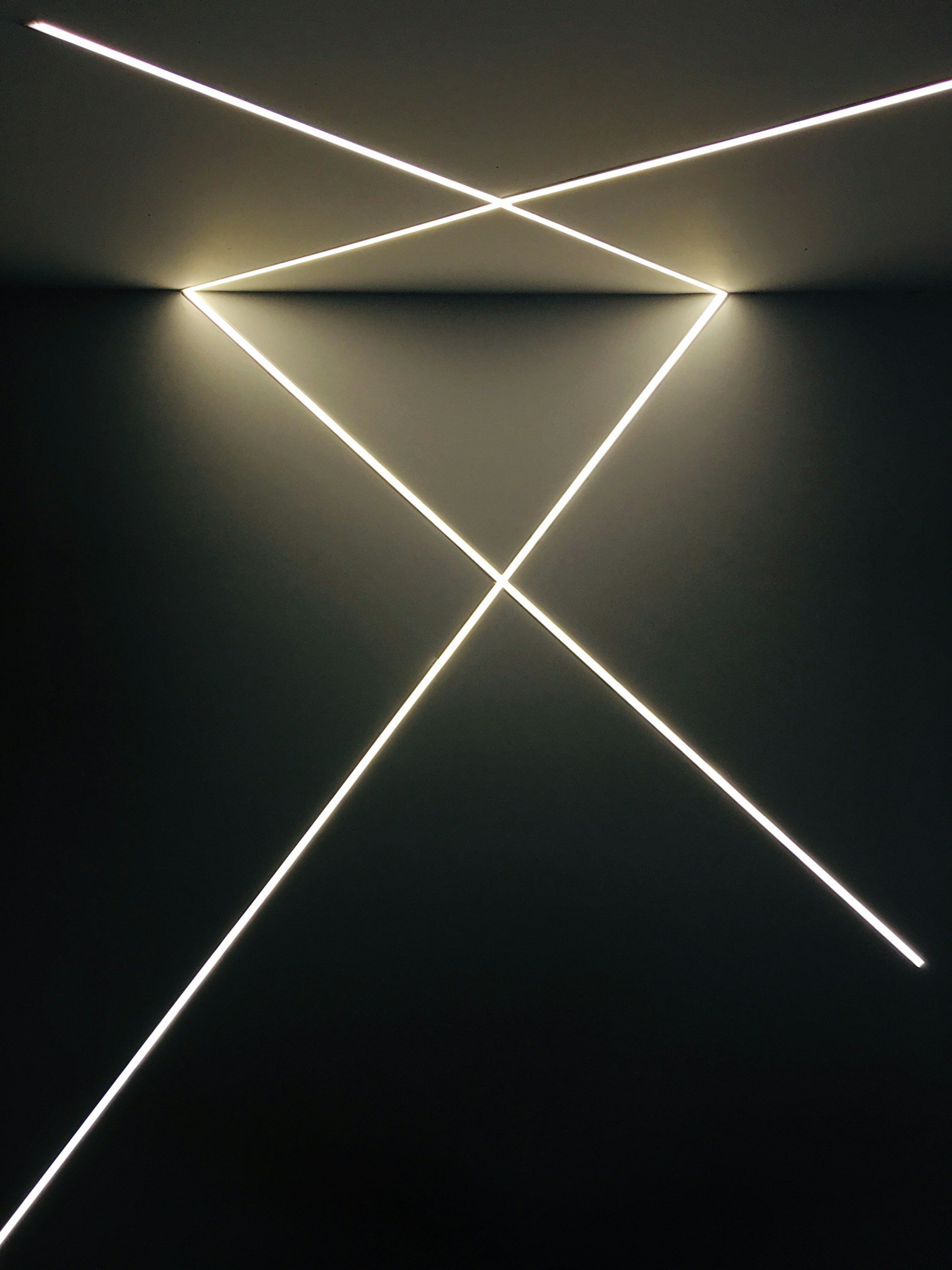 Black background with illuminated white neon lines forming an abstract geometric diamond shape.