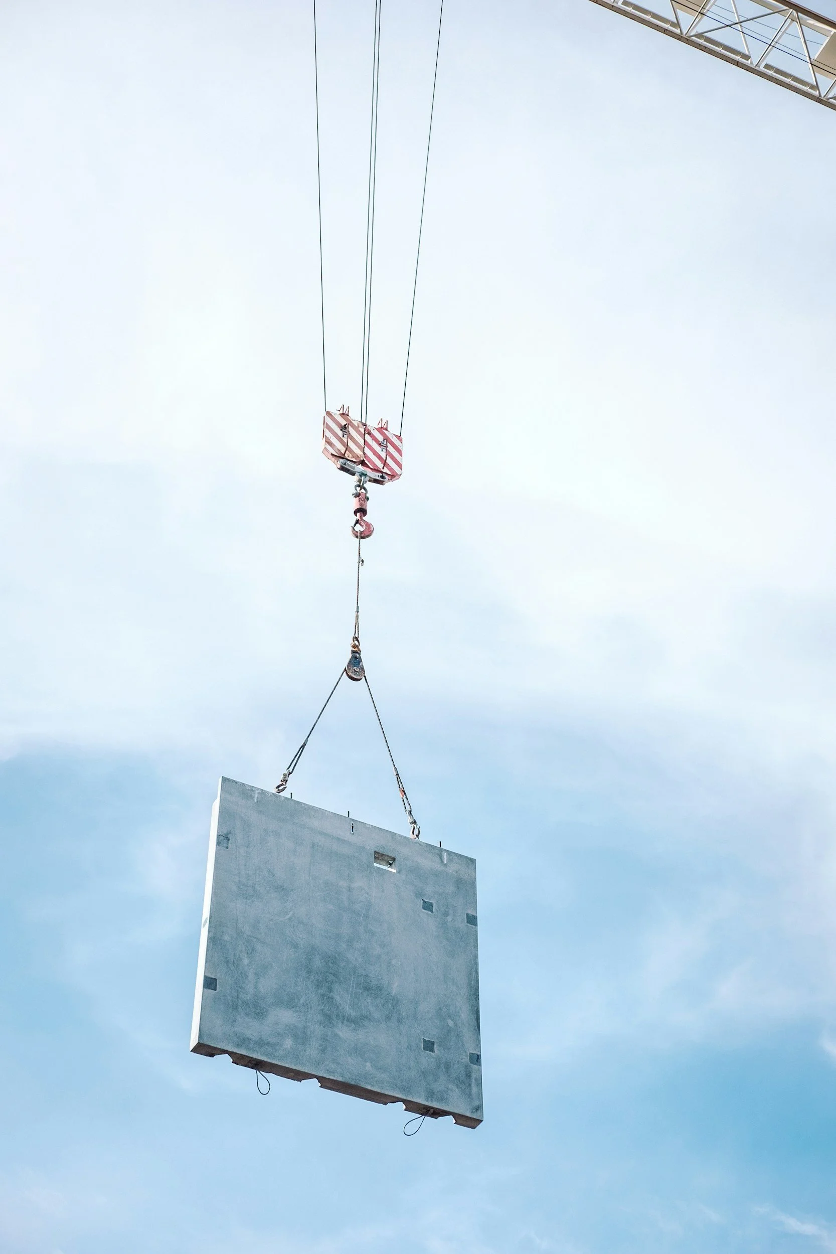 A crane lifting a large rectangular billboard against a cloudy sky.
