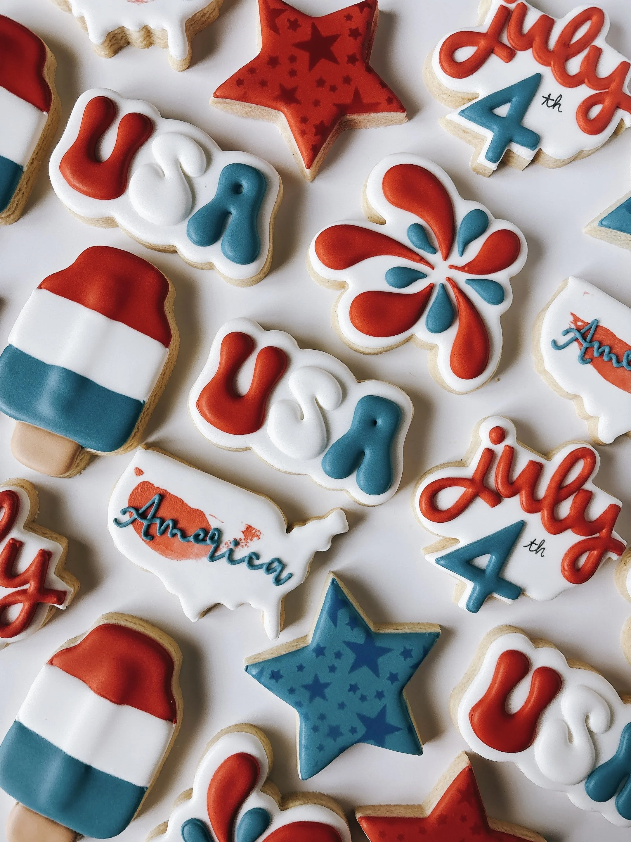 Decorated sugar cookies in red, white, and blue with messages and patriotic designs, celebrating a 4th of July or Memorial Day.