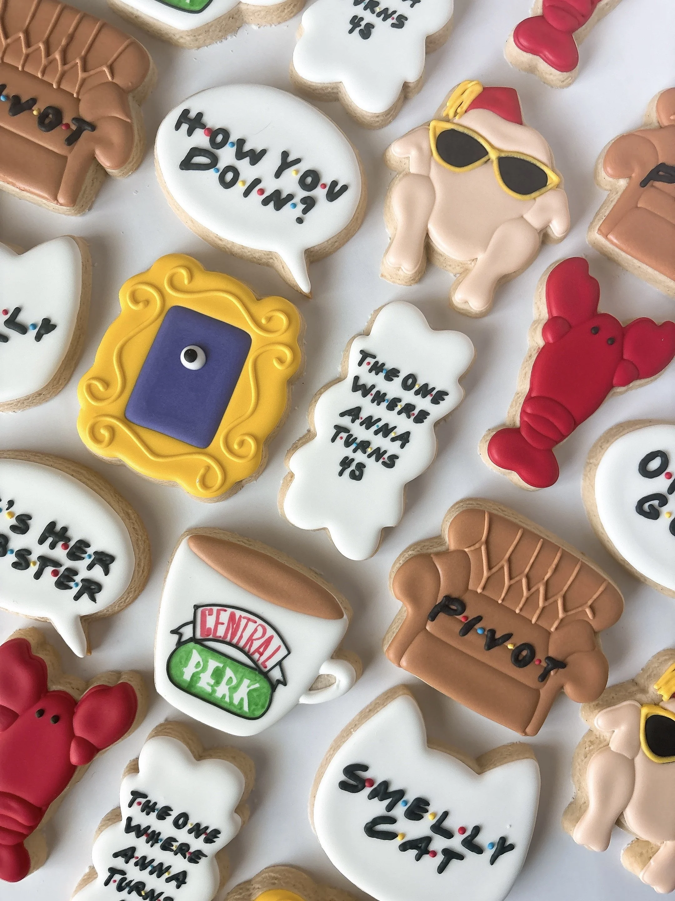 Collection of decorated cookies with various messages and characters, including a speech bubble cookie saying "HOW YOU DOIN?" and a cookie with a person wearing sunglasses and a Santa hat.