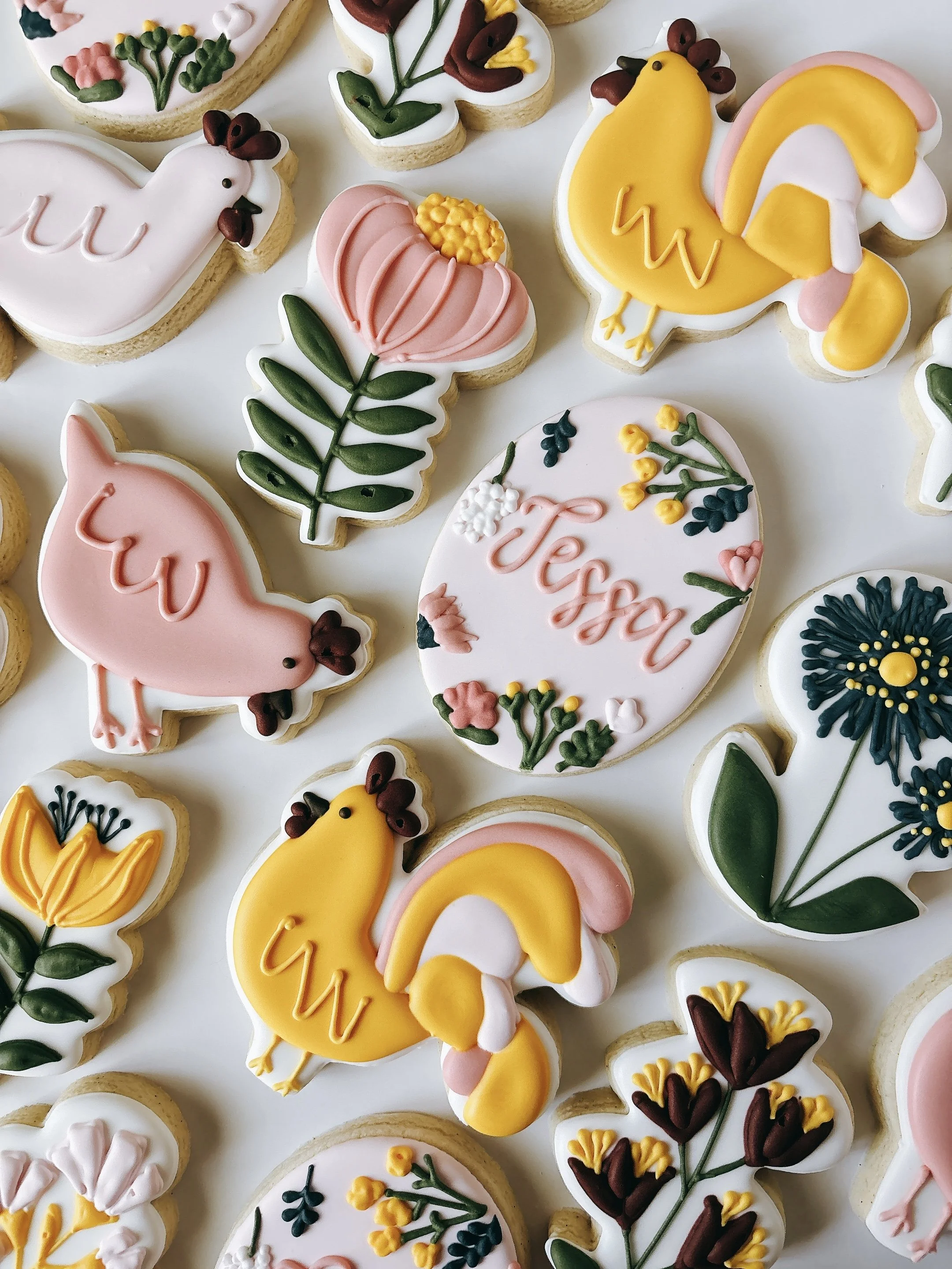 Assorted decorated sugar cookies with floral and seasonal designs, including a bird, a peach, and a chick.