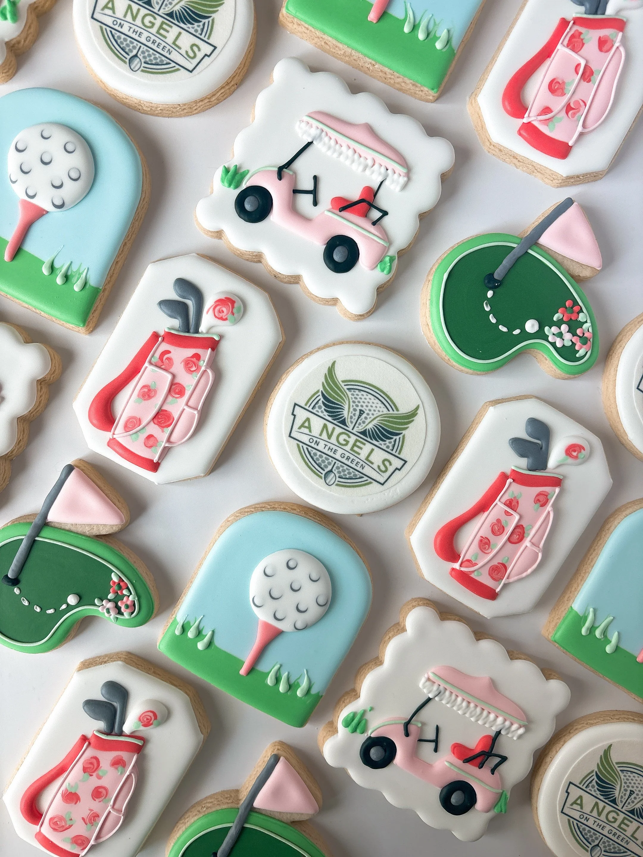 Assorted decorated cookies featuring golf clubs, golf balls, golf carts, and logos related to Los Angeles on the green.