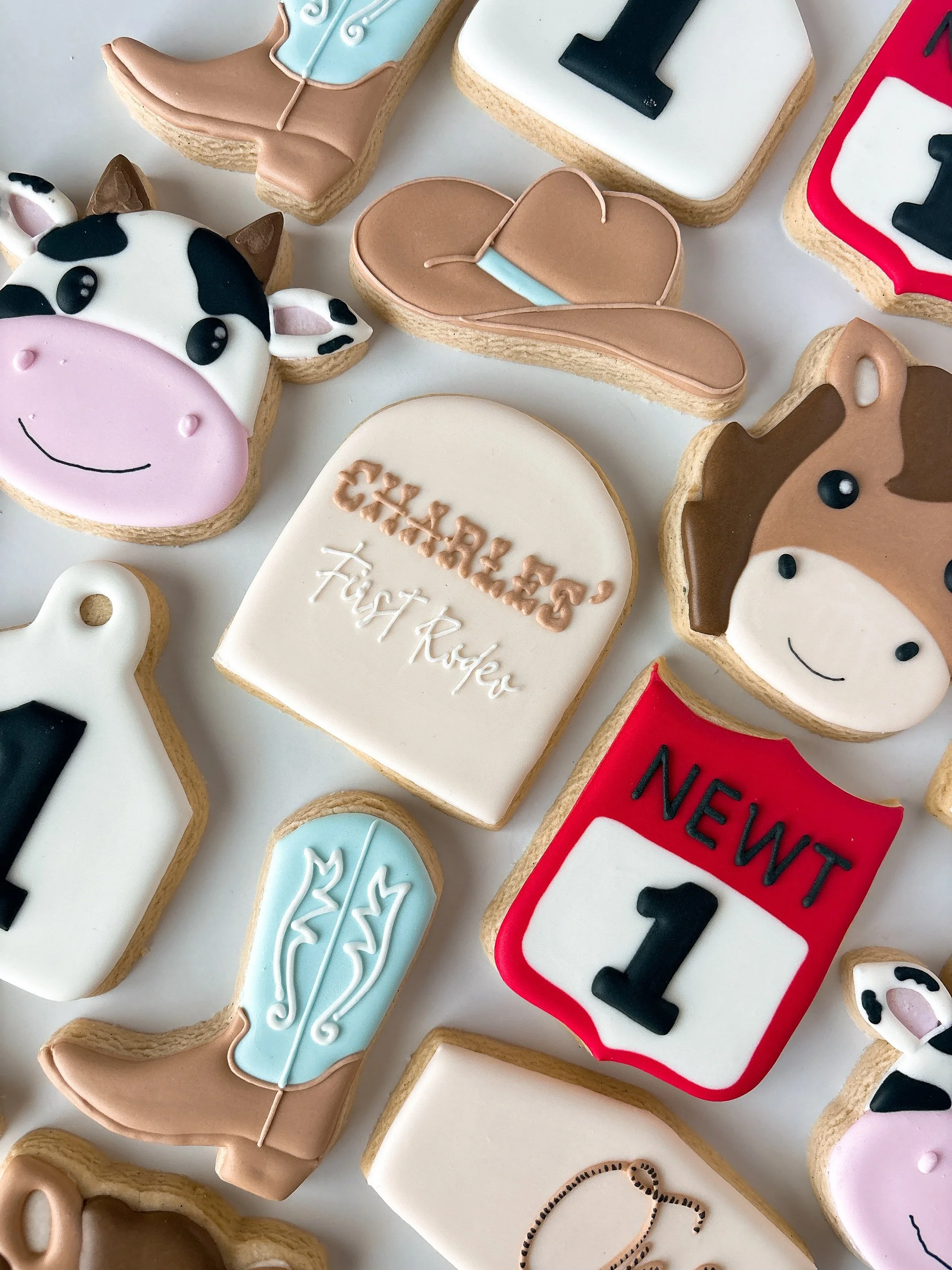 Decorative cookies with various themes including cow, horse, and birthday messages, decorated with colorful icing.