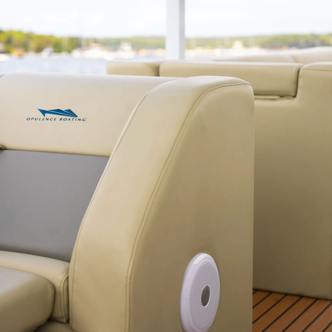 Interior of a boat with cream-colored seating and a view of water and boats outside the window.