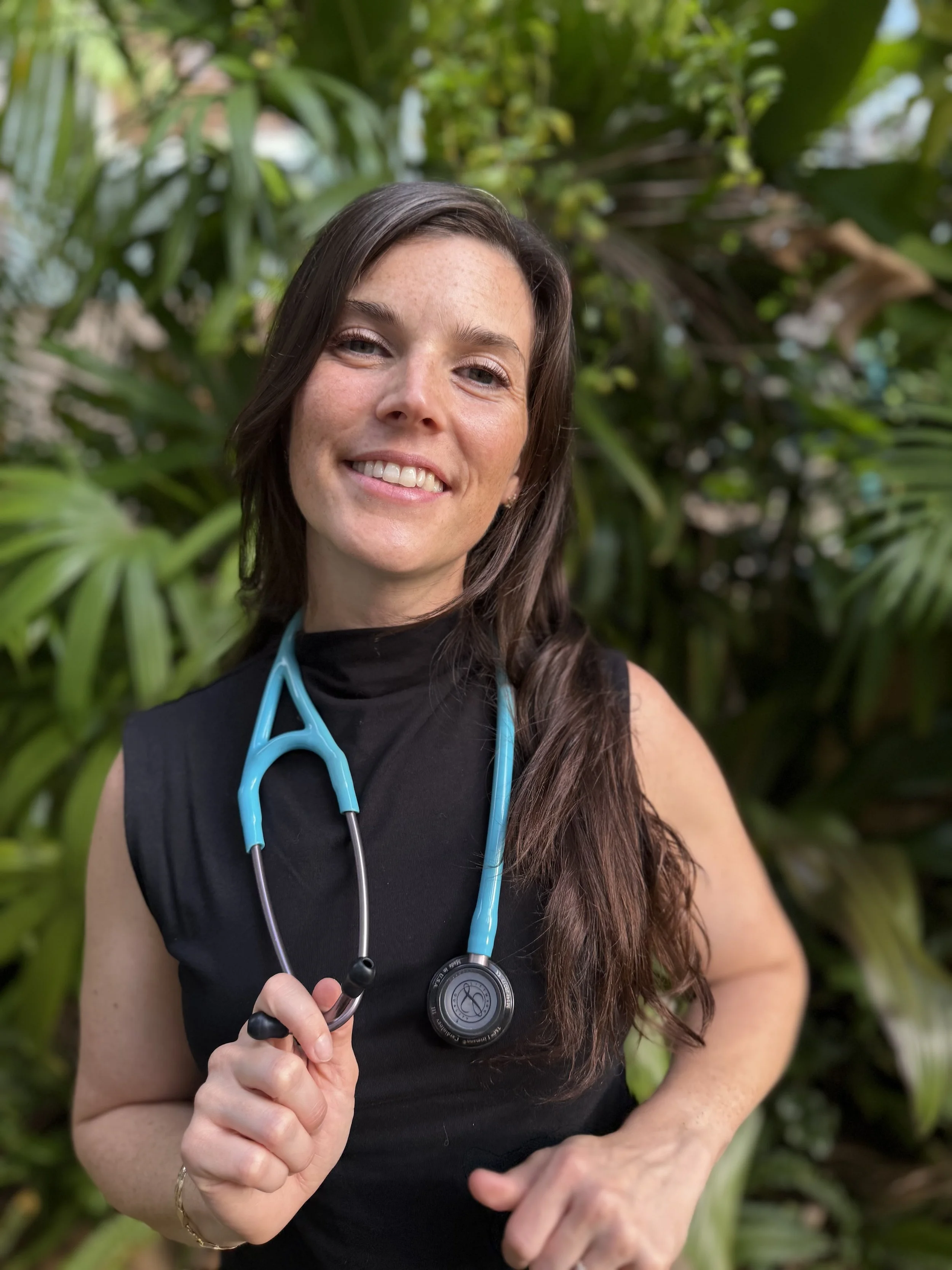 Meghan Twomey, APRN, holding a blue stethoscope, smiling while growing a community of thriving NPs