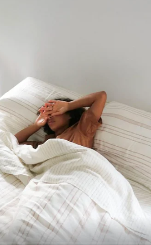Woman resting beneath a lightweight, breathable cotton muslin blanket
