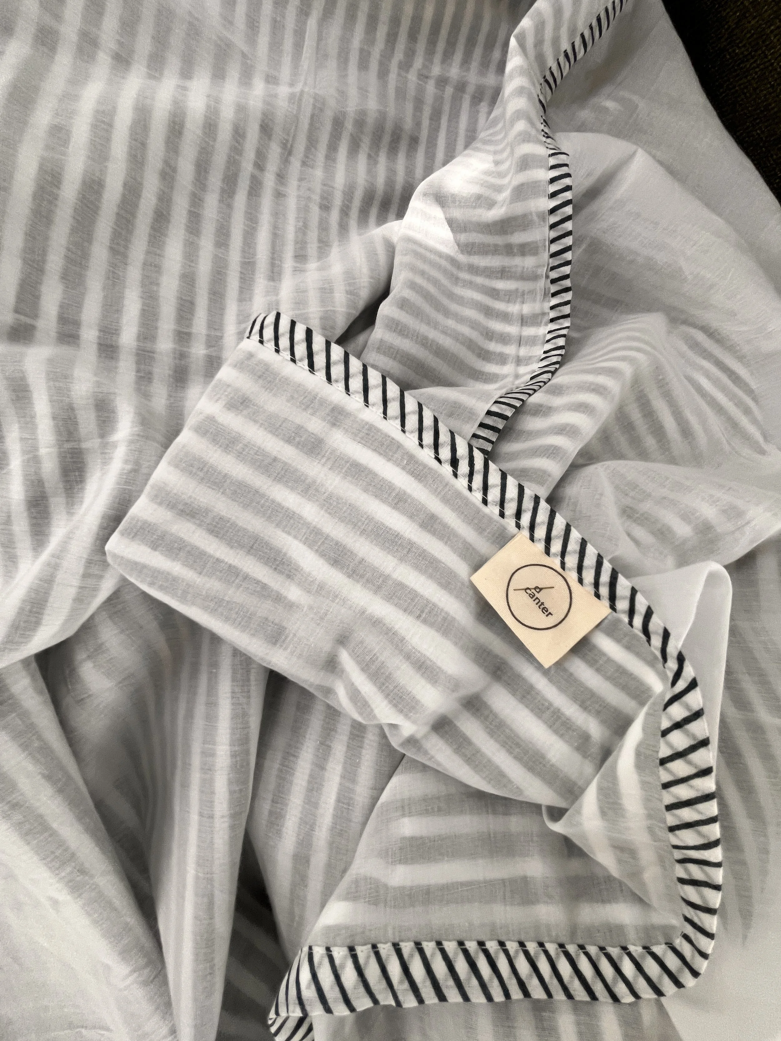 Close-up of a striped d/canter cotton muslin blanket showing its texture and brand label