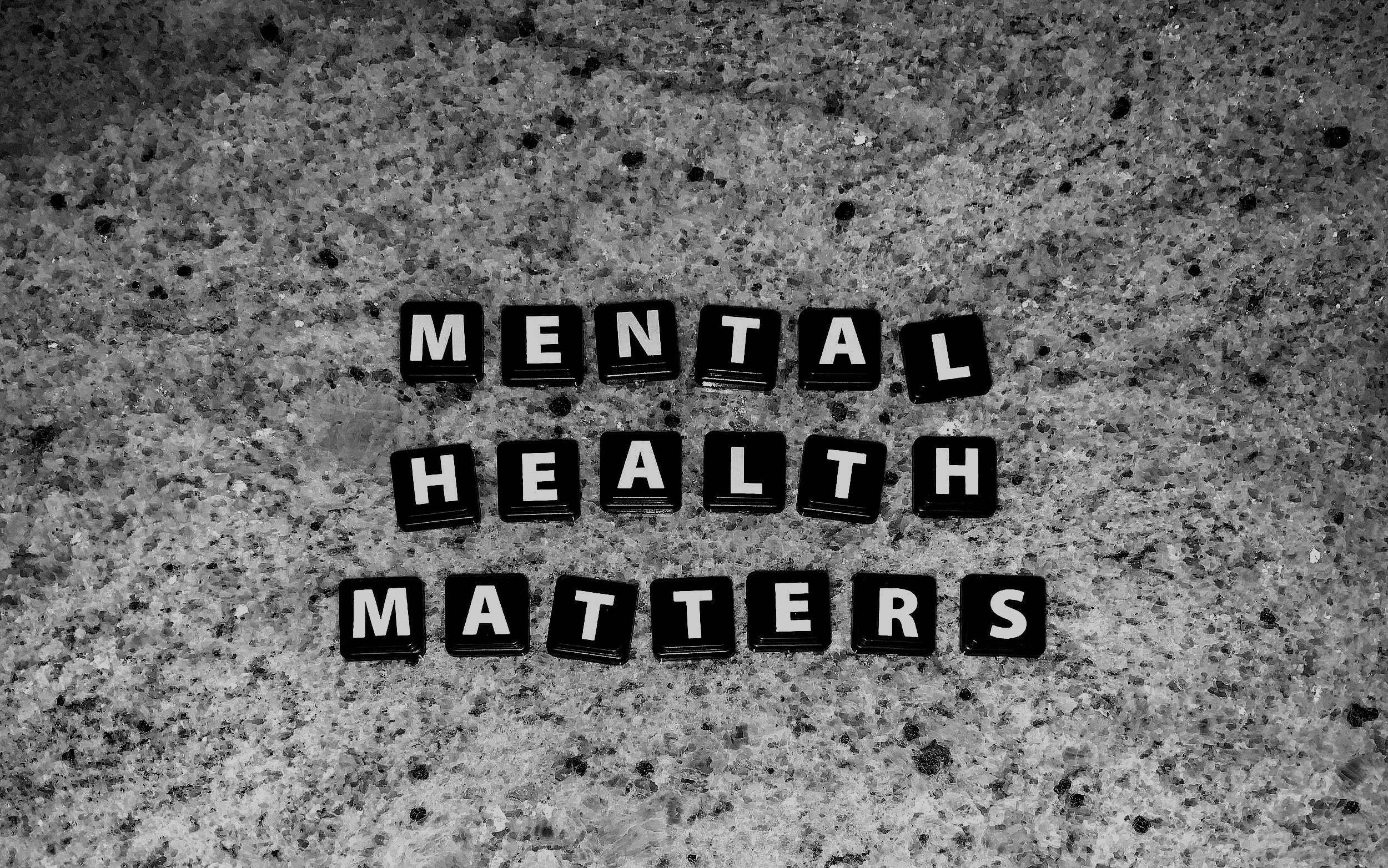 Black letter tiles spelling out 'MENTAL HEALTH MATTERS' are scattered on a speckled gray surface.