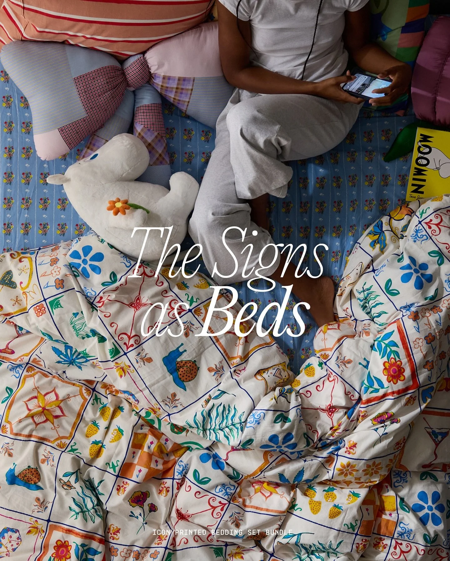 A person sitting on a bed with colorful, patterned bedding, holding a smartphone. The bed is decorated with various pillows and stuffed animals. The image features an overlay text that reads "The Signs of Beds" and some additional text at the bottom 