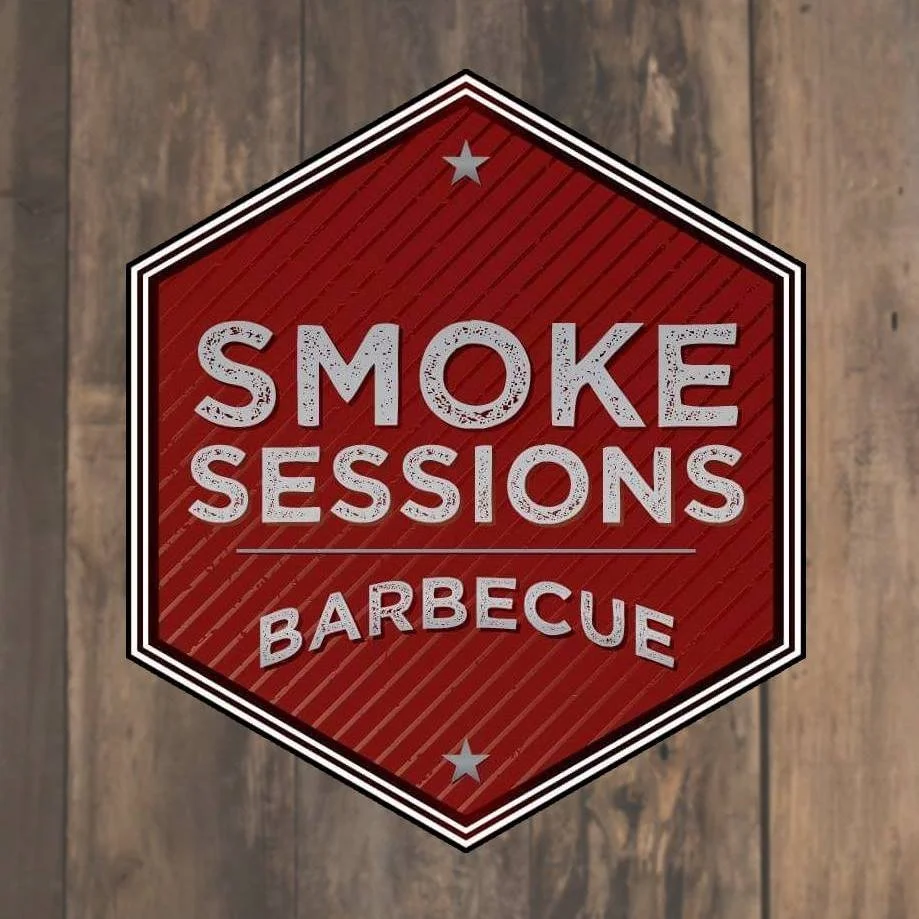 Red and black sign with white text saying 'Smoke Sessions Barbecue' on a wooden background.