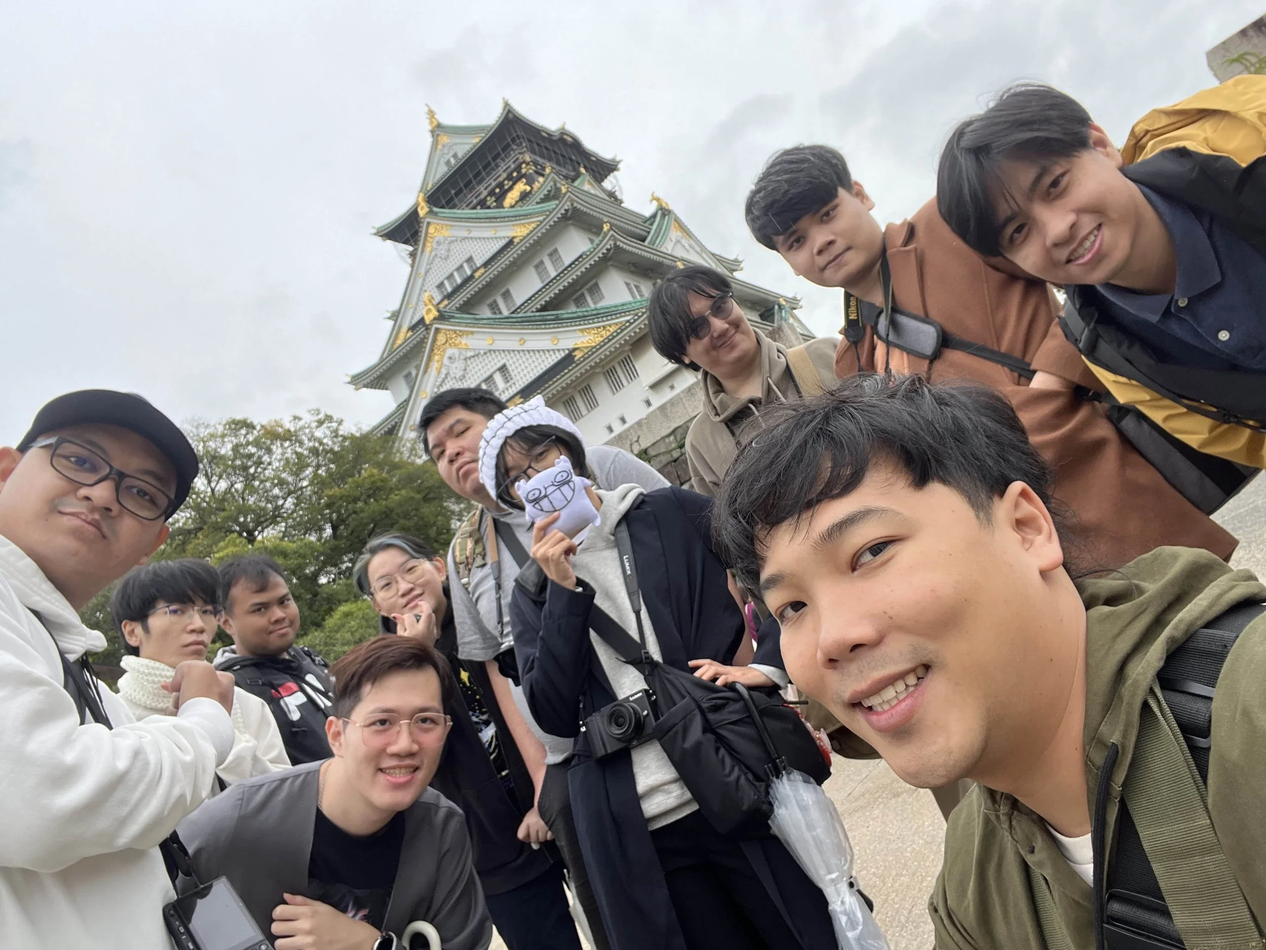 Group of people taking a selfie in front of a traditional Japanese castle.