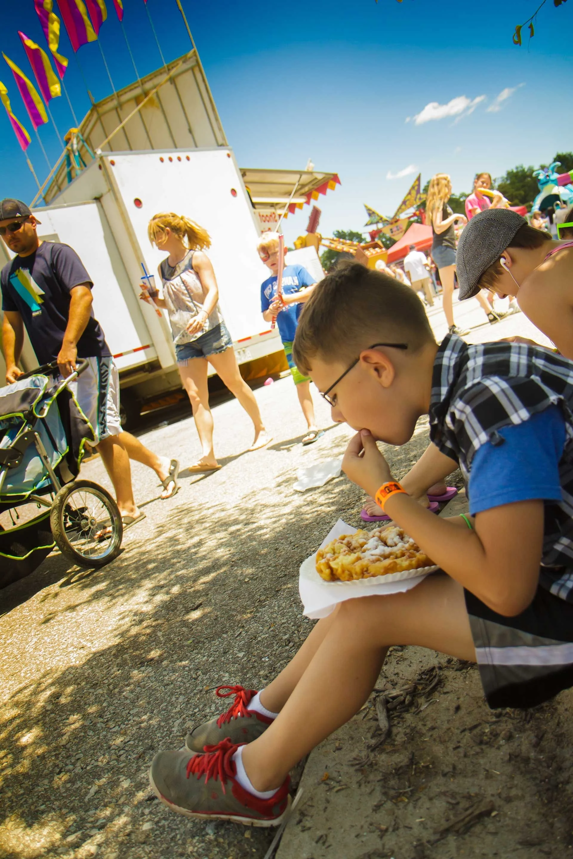 a young boy eating a snack on the sidewalk