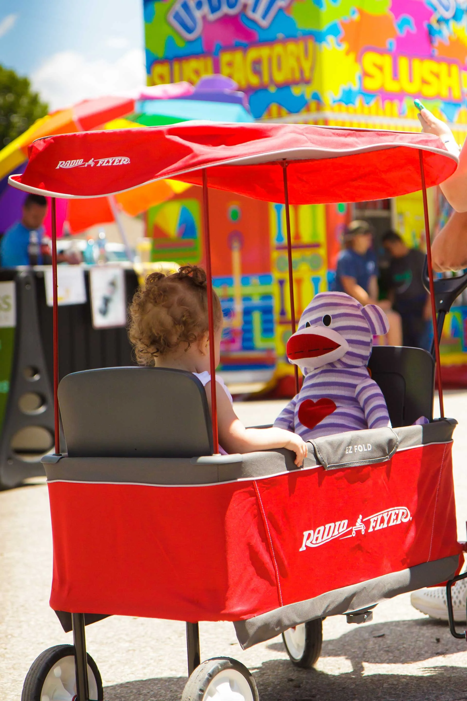 A little girl riding in a red wagon