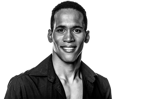 Black and white portrait of a smiling man wearing a dark shirt.