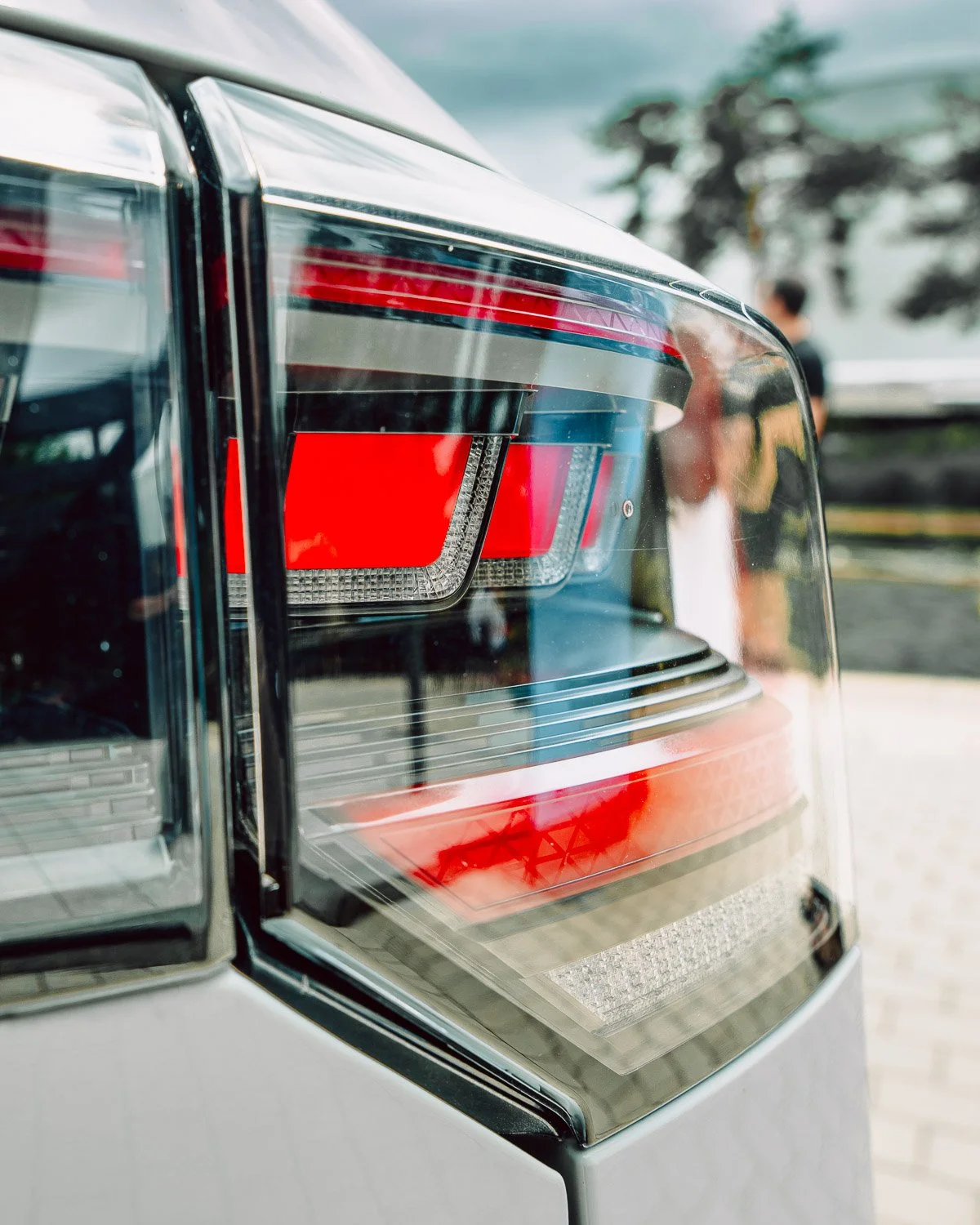 Close-up of a car's tail light with a person in the background.