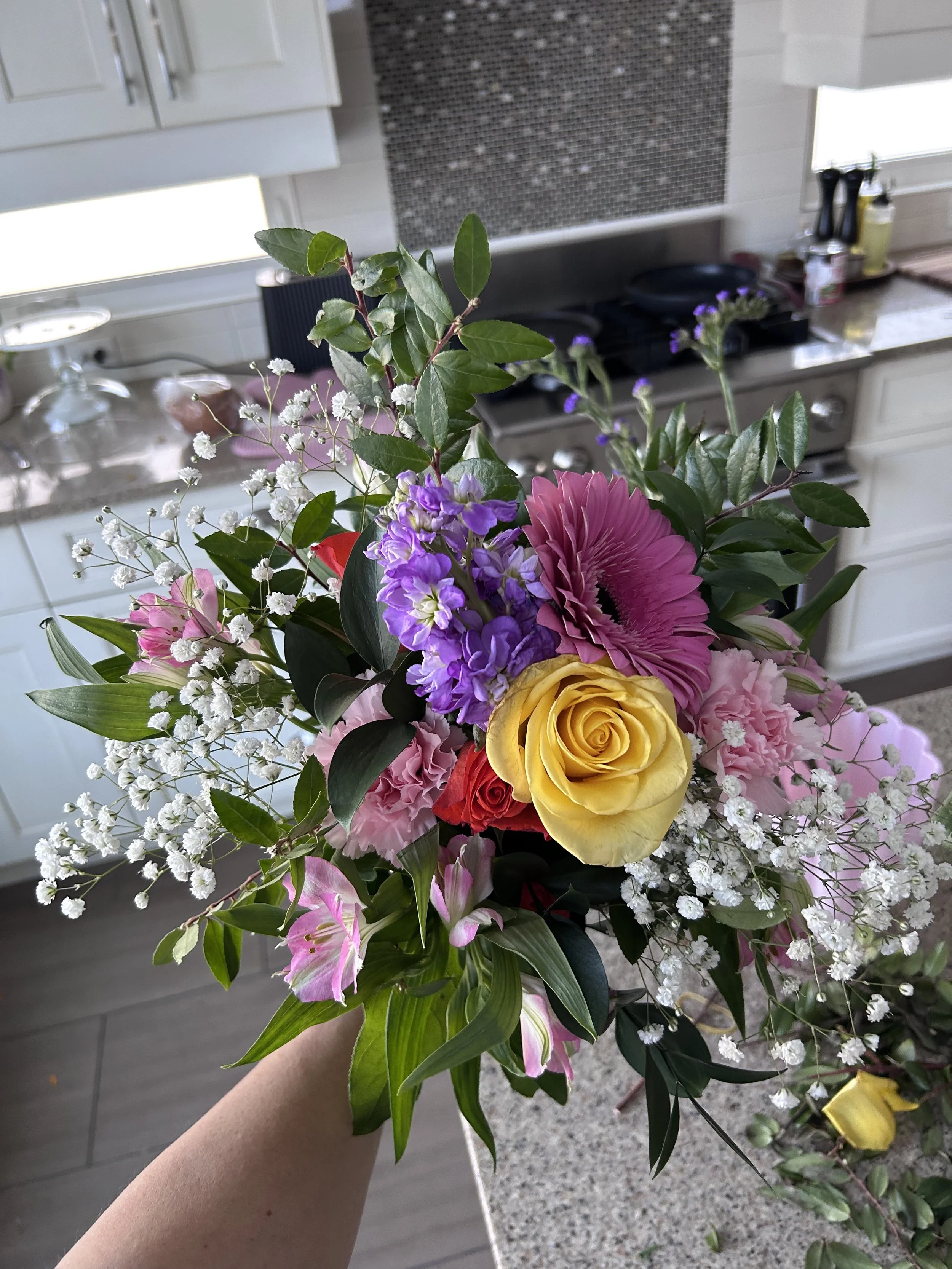 Early practice bouquet with a yellow rose, pink gerbera, purple stock and baby's breath.
