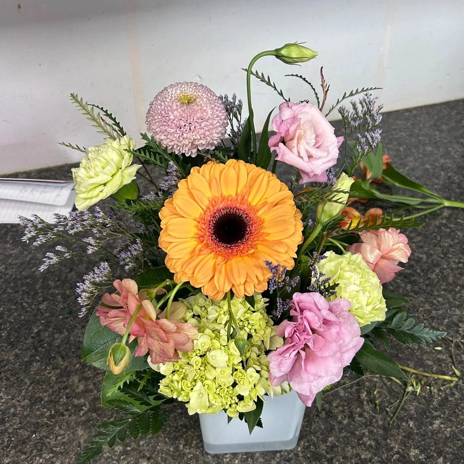 Orange gerbera arrangement with pink roses and green hydrangea, my first arrangement built at a flower shop.