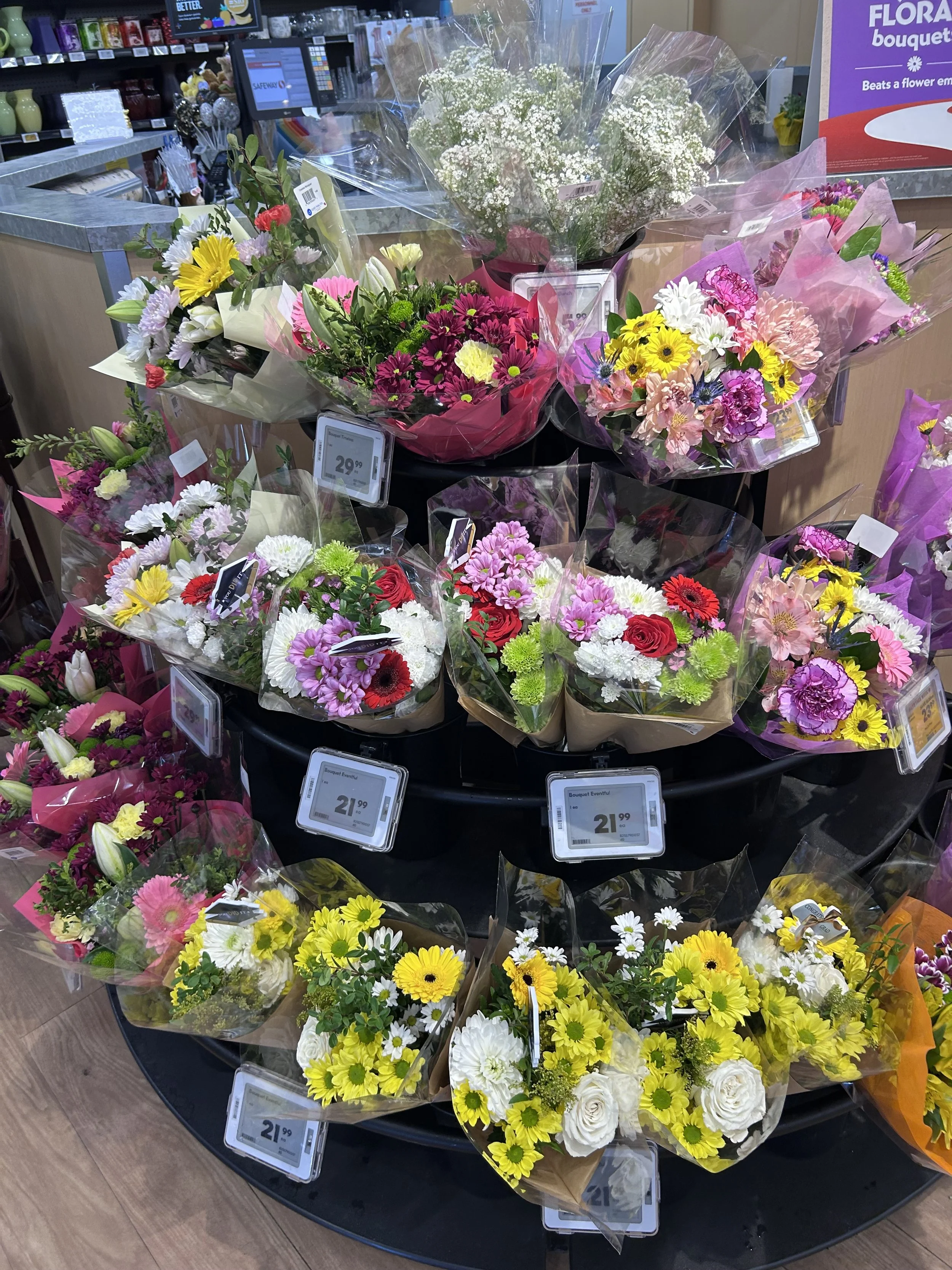 Bouquets of mixed flowers on display at a grocery store flower stand.