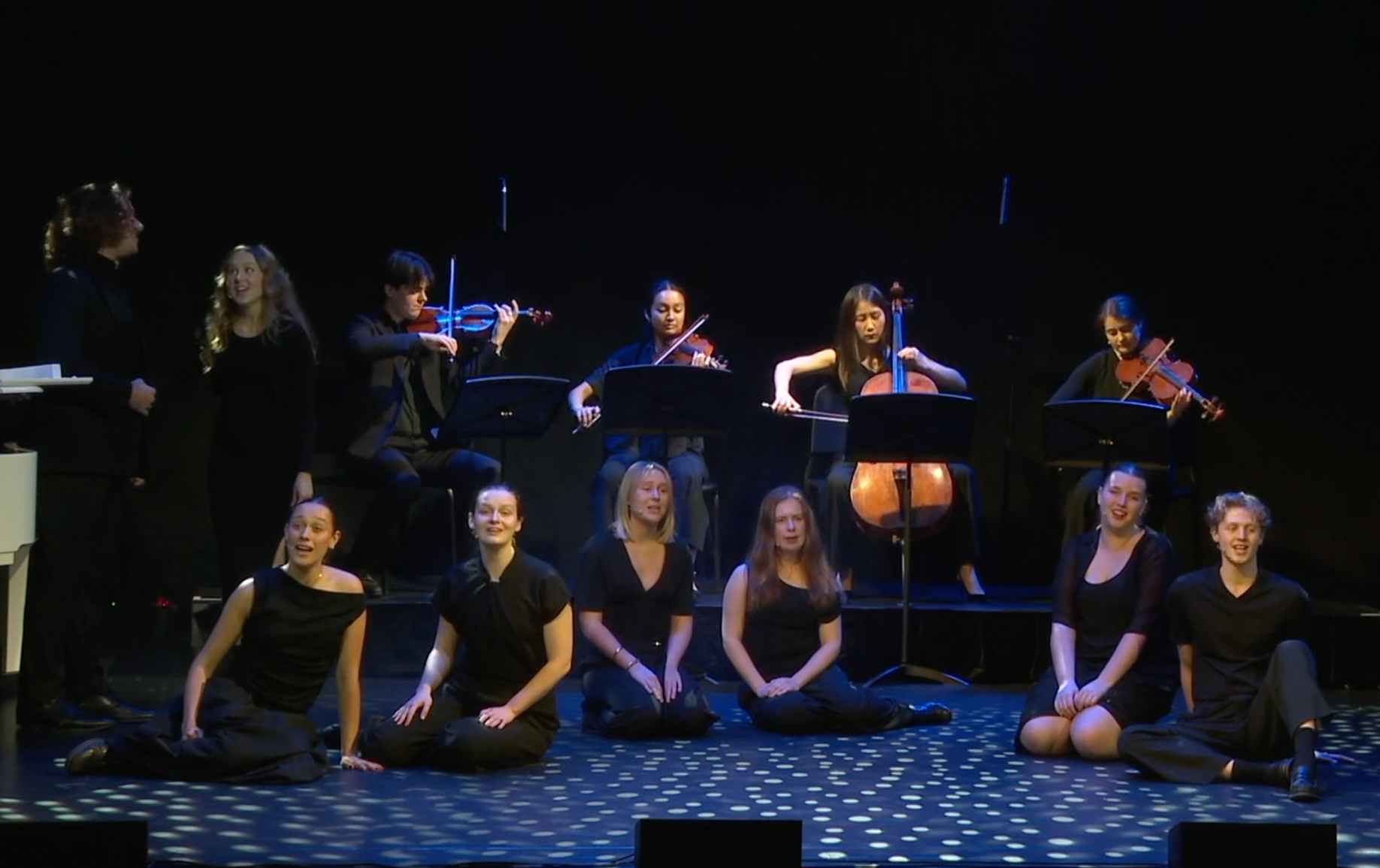 A group of Pursuit 19 musicians and singers on stage during a performance at the Footbridge Theatre. 