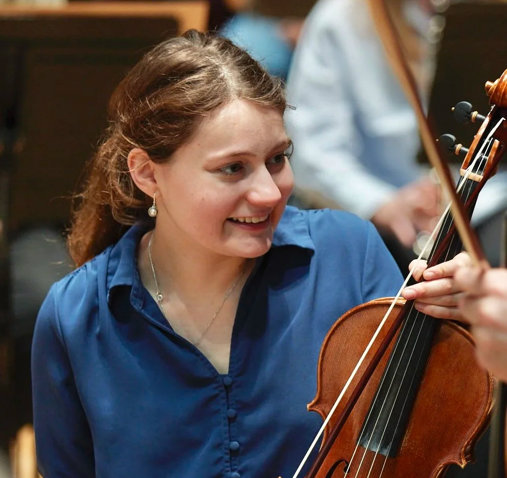 Musician smiling while playing the viola at an orchestra rehearsal. Sydney string musician