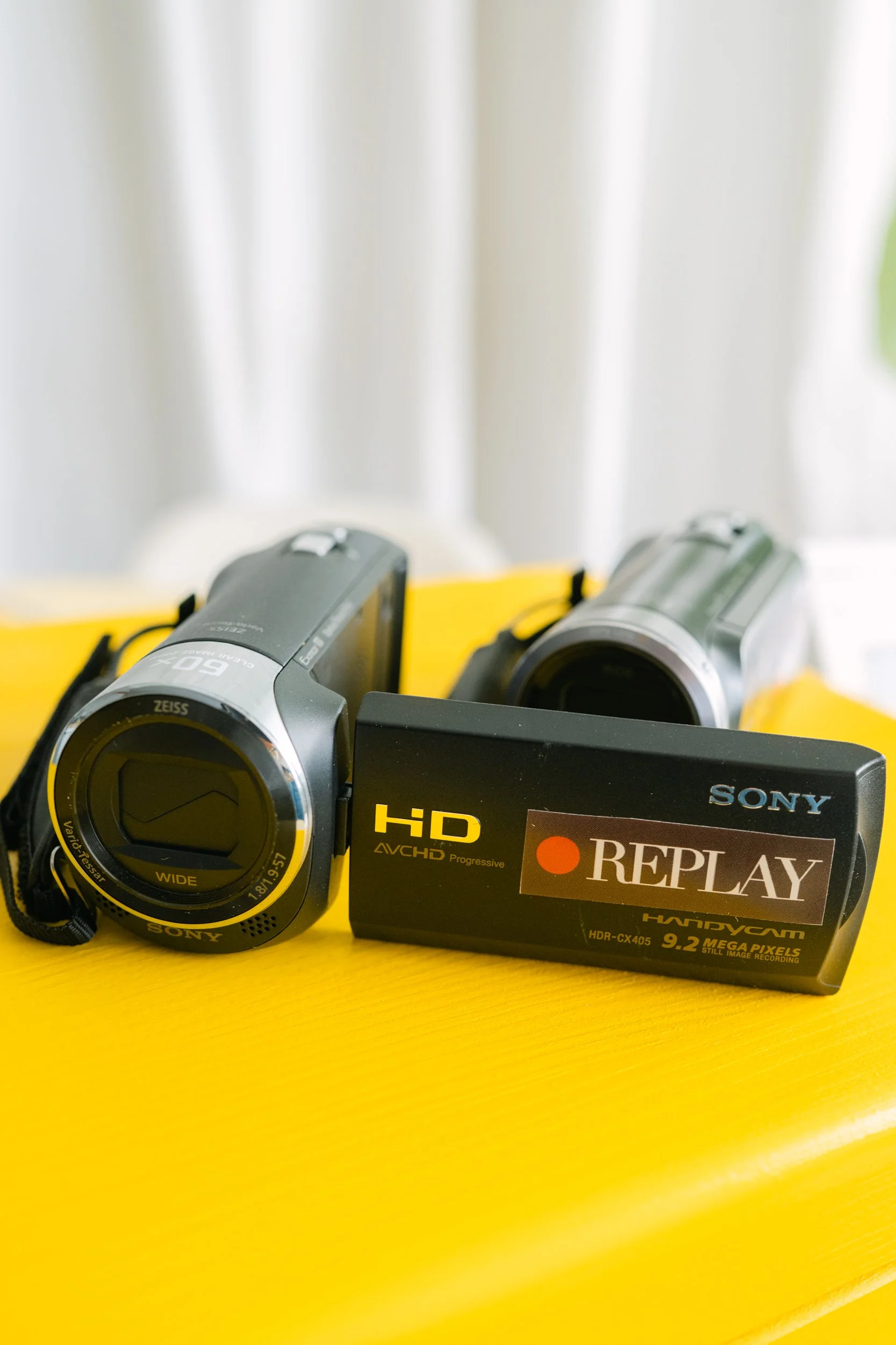 camcordere rental  video camera with Sony branding, black box labeled REPLAY, yellow background surface, and data recording specifications.