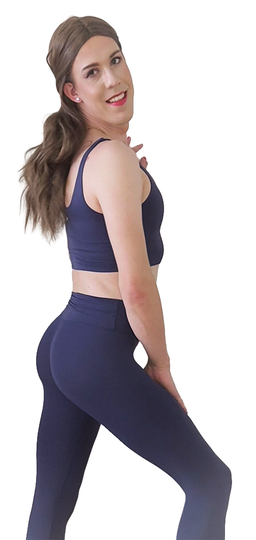 Lauren with long brown hair, wearing a navy sports bra and matching leggings, standing with her left hand on her left thigh and smiling at the camera.
