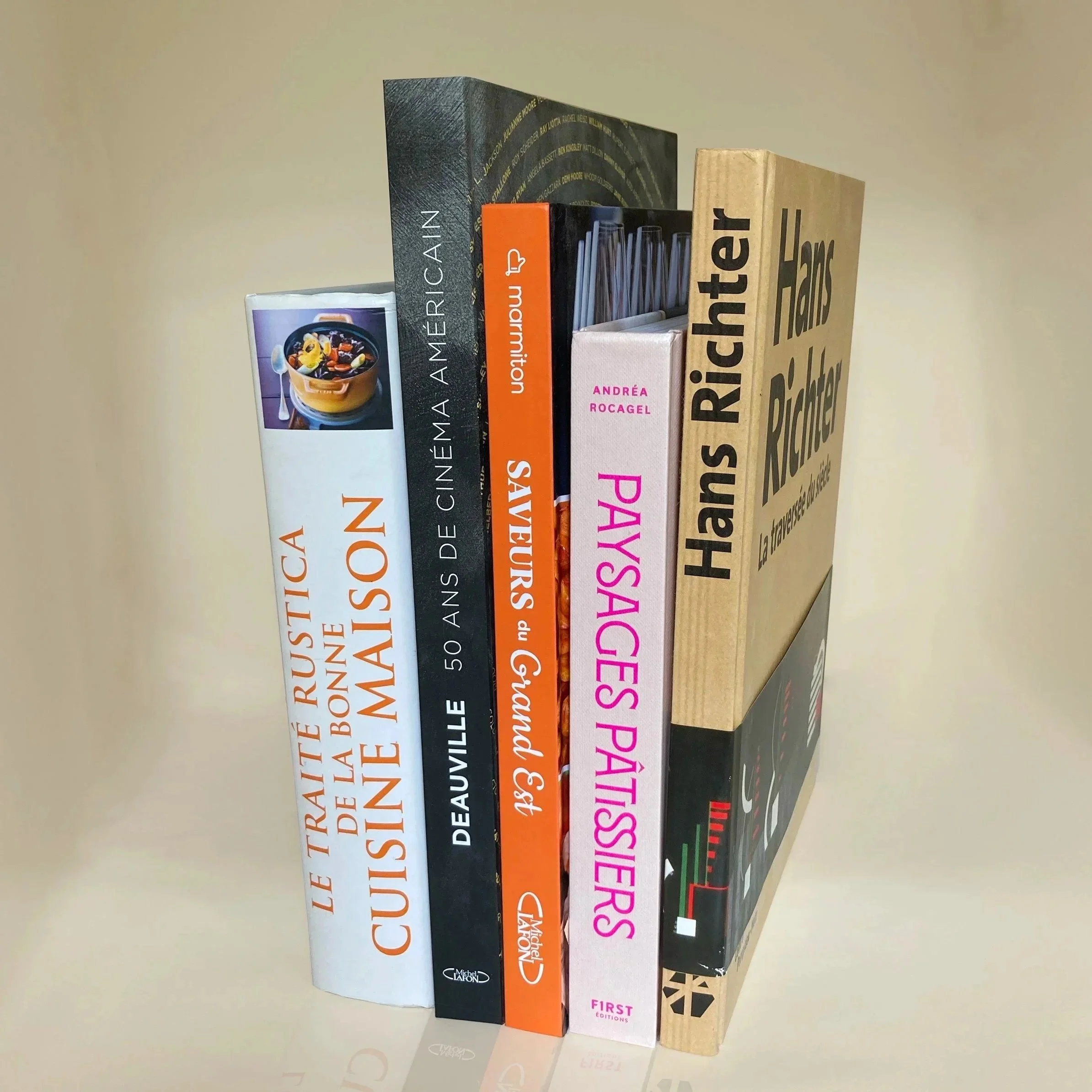 Une rangée de livres divers posés verticalement sur une surface plane, certains avec des titres visibles en français.