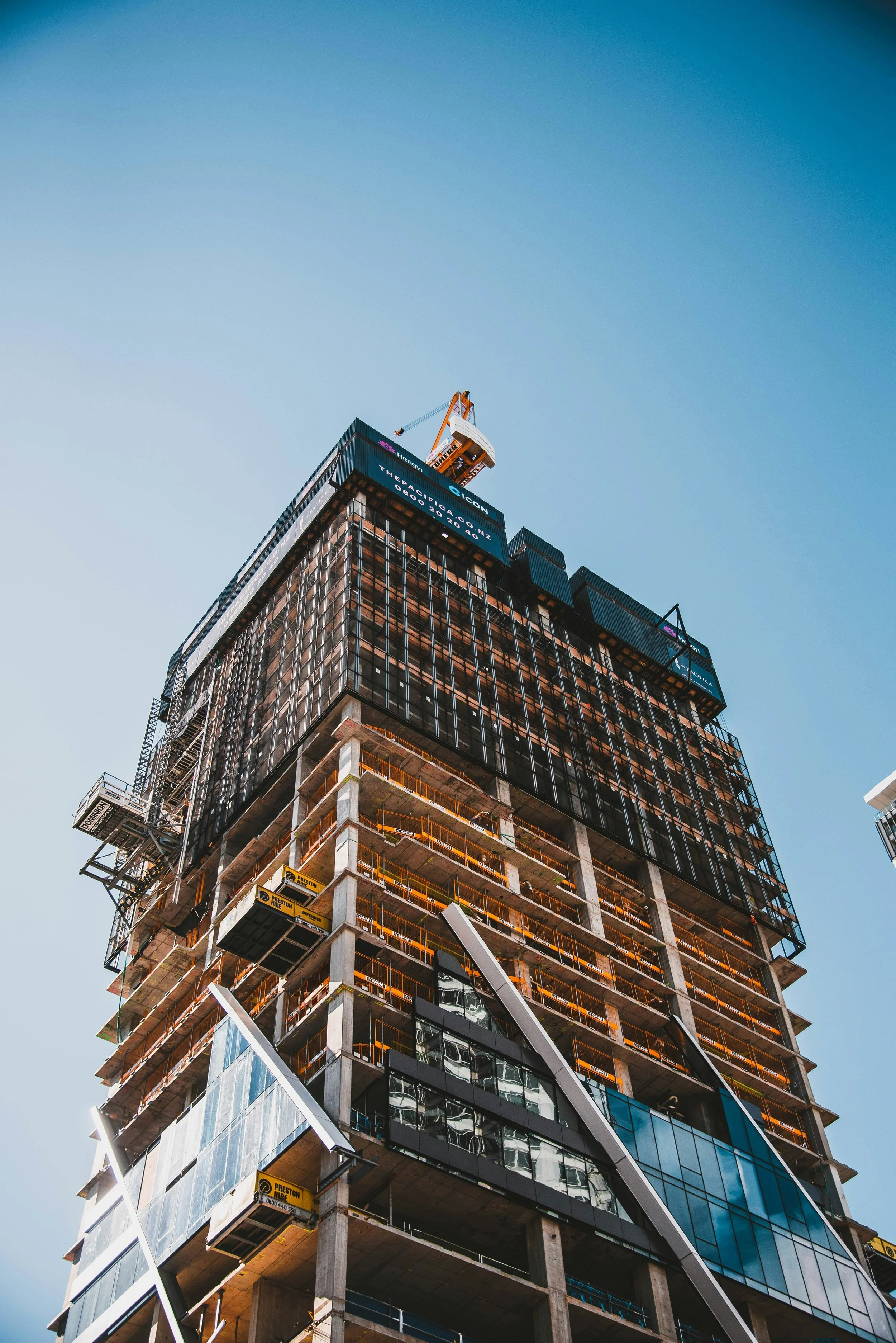 Real Estate - housing . Apartment building under construction with a crane on top, glass windows, and structural framework visible