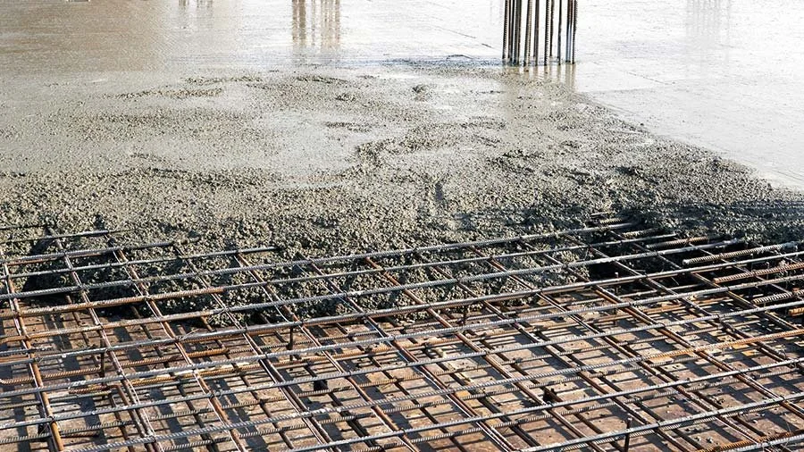 Reinforced concrete being poured over a steel rebar reinforcement on a construction site.