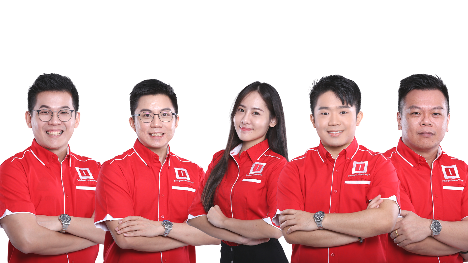 Group of five diverse young professionals standing together with crossed arms, smiling, wearing red shirts with a white logo, against a white background.