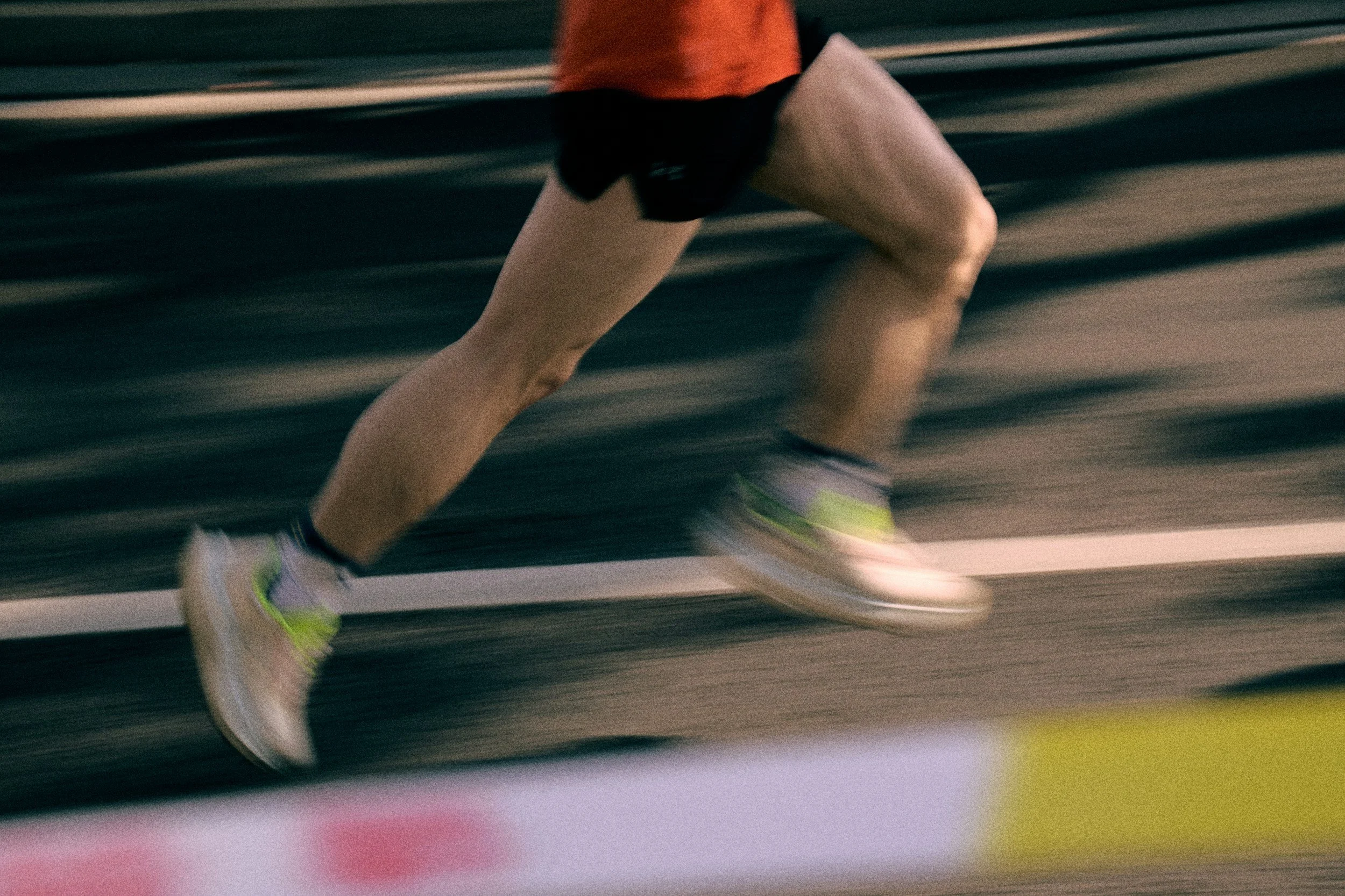 A runner's legs and feet in motion during a race, wearing athletic shoes, with blurred background indicating speed.
