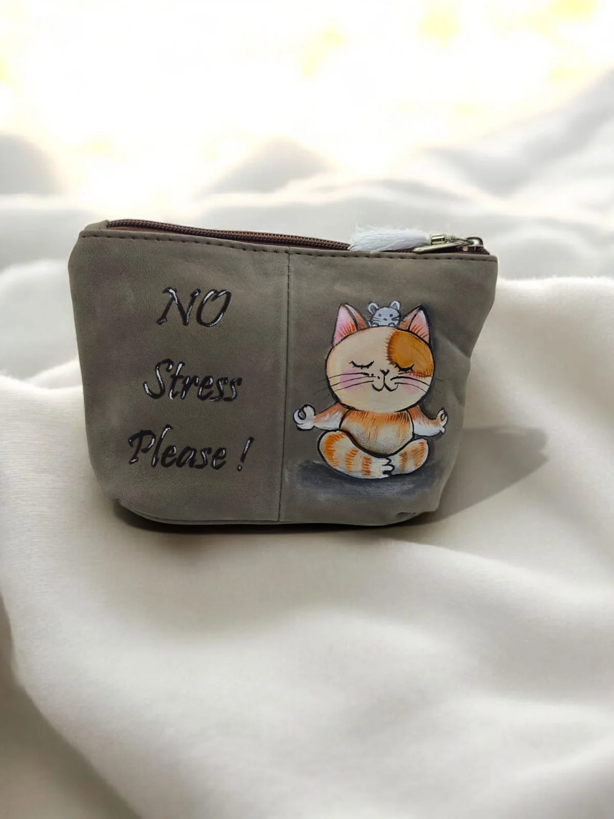 Una piccola borsetta di colore grigio con disegni di un gatto in meditazione, una frase che dice 'No Stress Please!' e un topolino sulla testa del gatto.