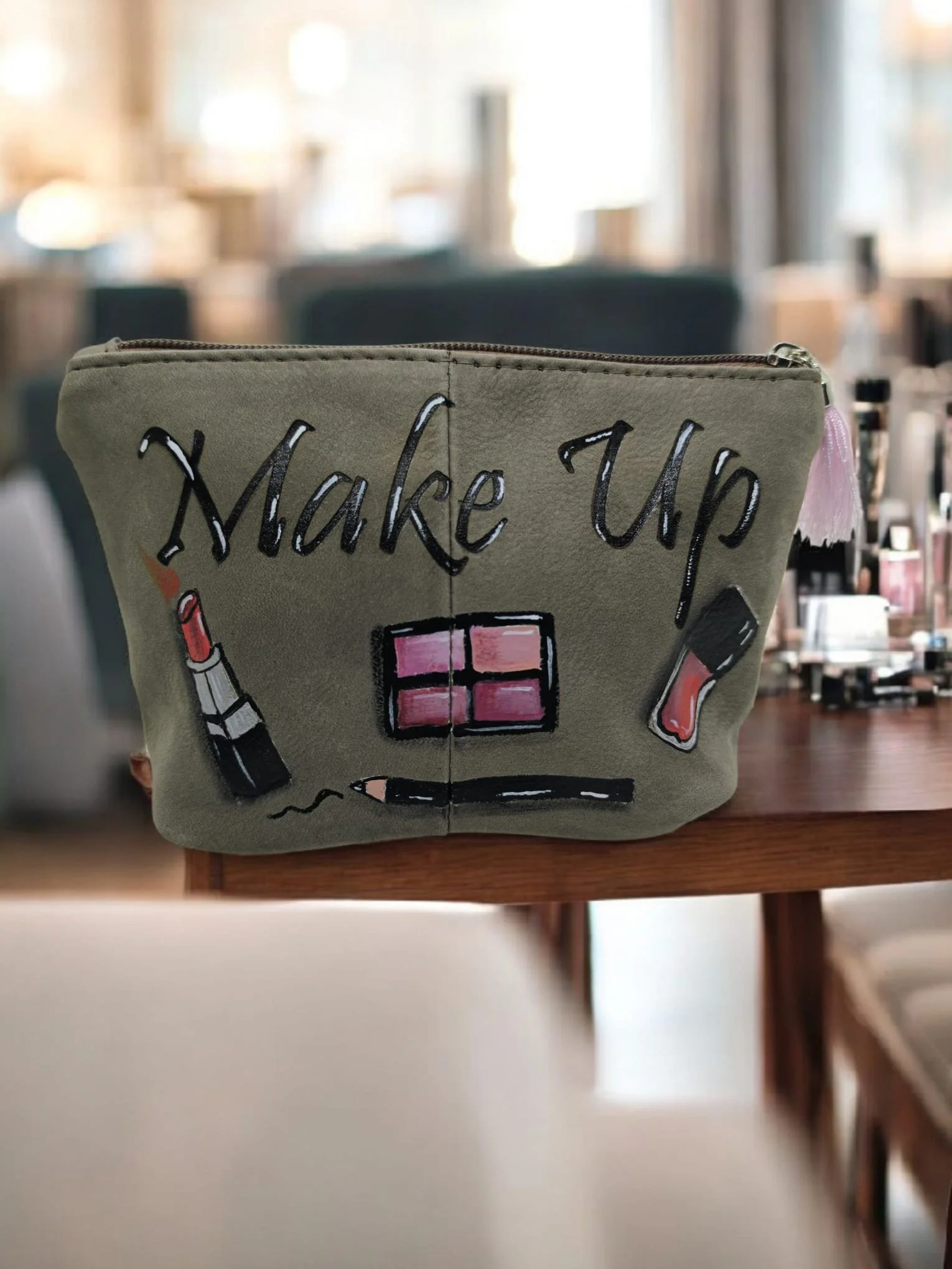 Una borsetta beige con scritta 'Wake Up' e disegni di rossetto, pennello e smalto per unghie, posizionata su un tavolo in un ambiente ben illuminato.