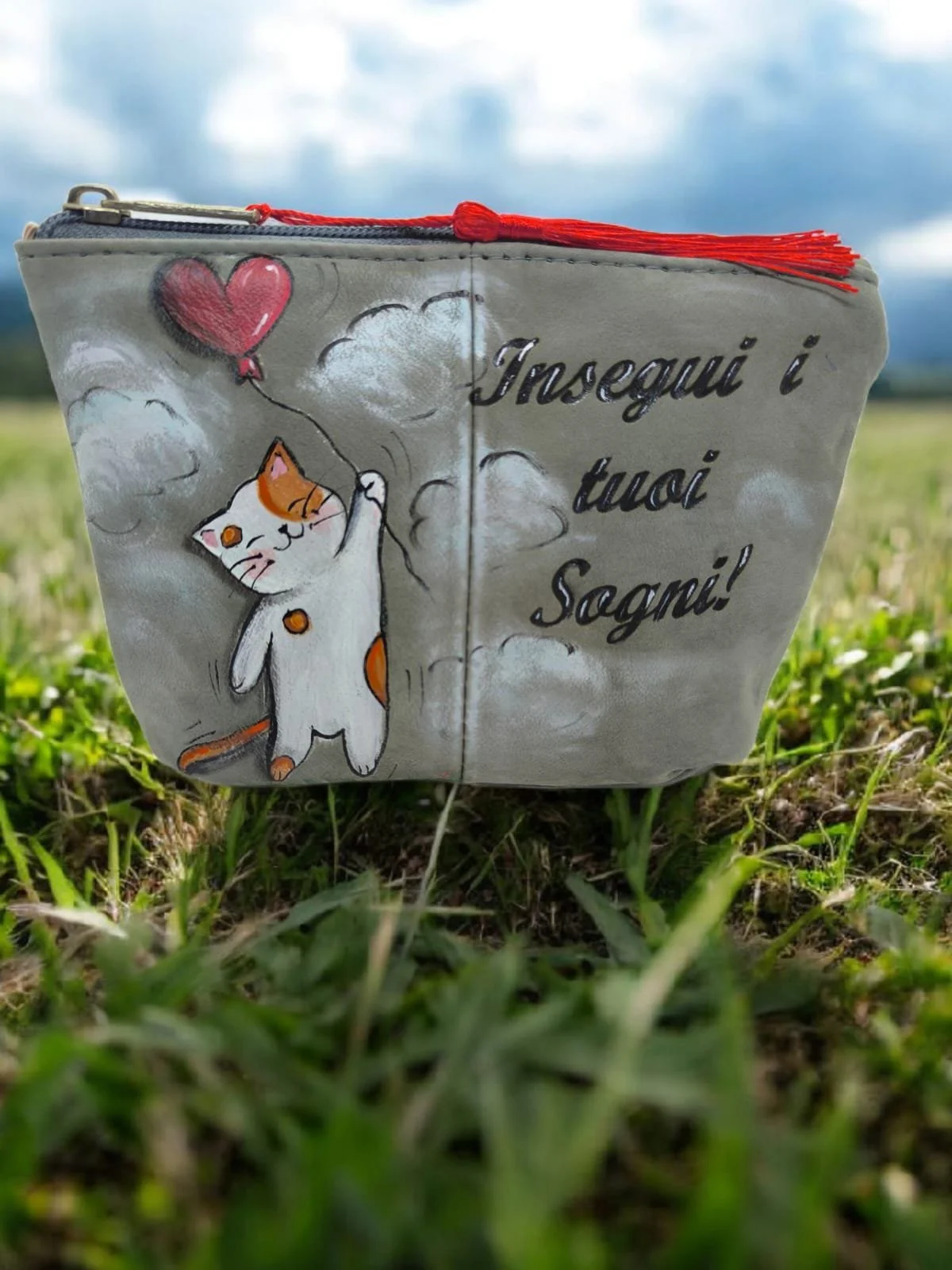 Borsa decorata con un gatto che tiene un palloncino a forma di cuore su uno sfondo di nuvole e con la scritta "Insegni i tuoi Sogni!".