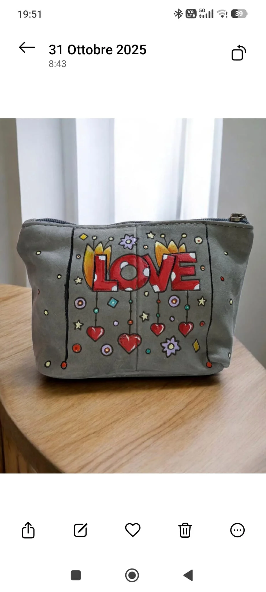 Una borsa grigia decorata con il disegno di frecce, fiori e cuori, con la parola 'LOVE' in rosso al centro.