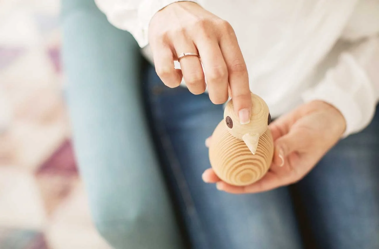 Hände halten eine handgefertigte Holzvogelfigur – Symbol für achtsame Begleitung im Coaching
