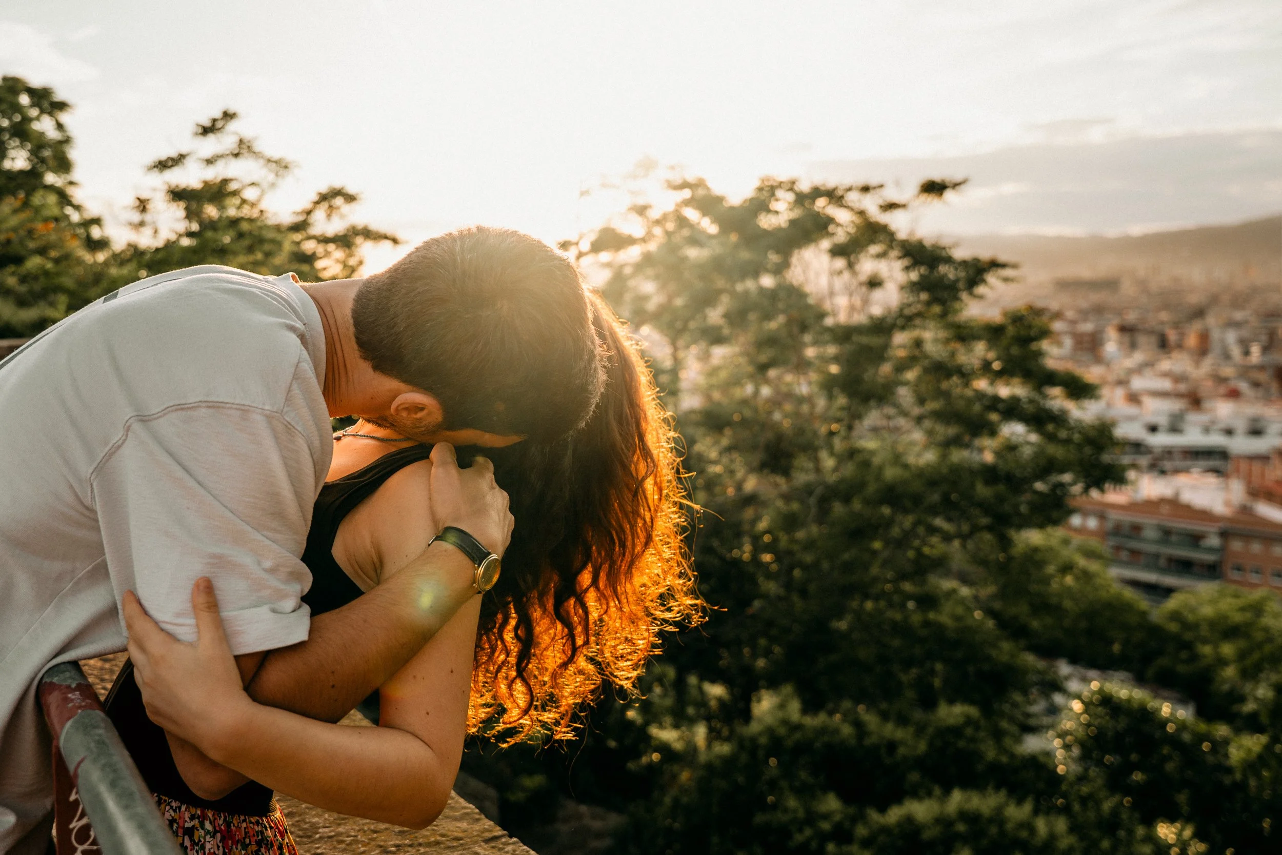 Couple embracing at golden hour with Barcelona cityscape in the background — Whip & Honey photography
