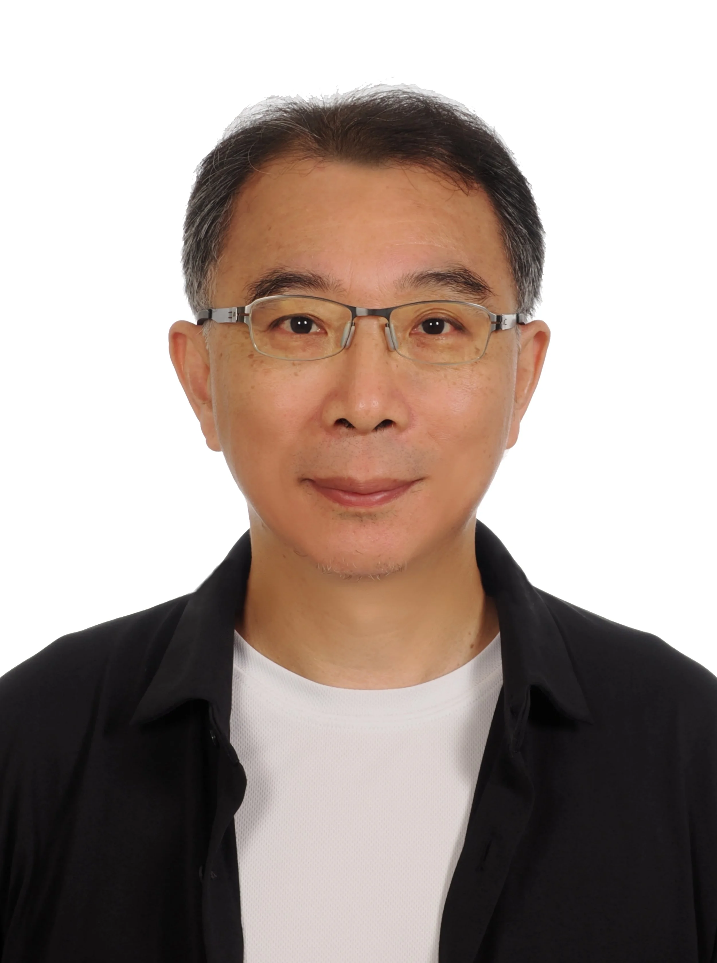Close-up of a man with short gray and black hair, wearing rectangular glasses, a black jacket, and a white T-shirt, standing against a white background.