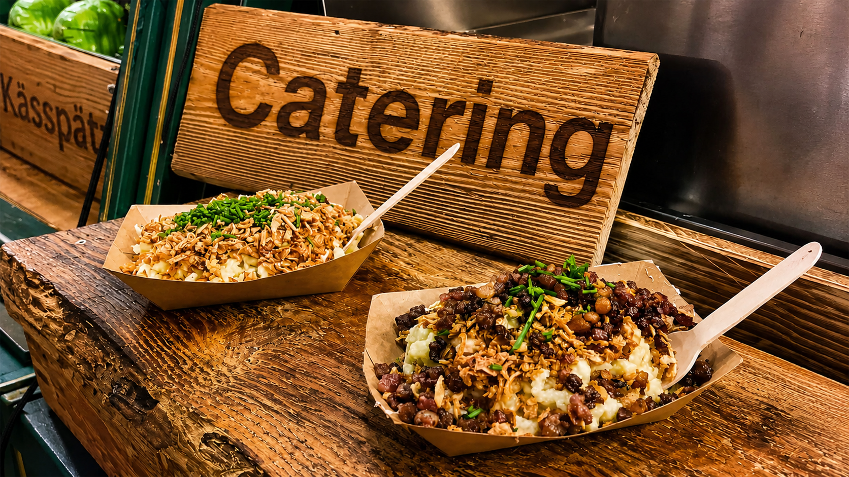 Zwei Gerichte mit Pasta und Linsen auf einem rustikalen Holztisch, Schilder im Hintergrund mit den deutschen Wörtern 'Catering' und 'Kässpätzle'.
