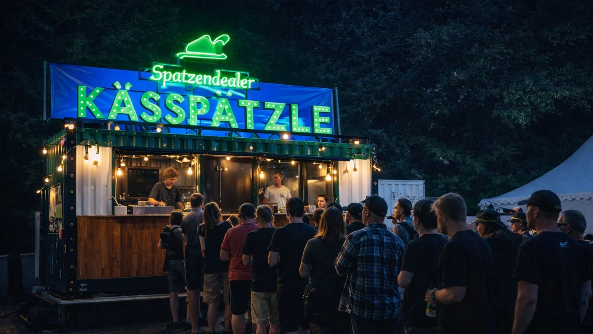 Menschen stehen vor einem Food-Truck mit leuchtendem Schild 'Kasspätze' und 'Spatzendealer' bei Nacht, im Hintergrund dunkler Wald.