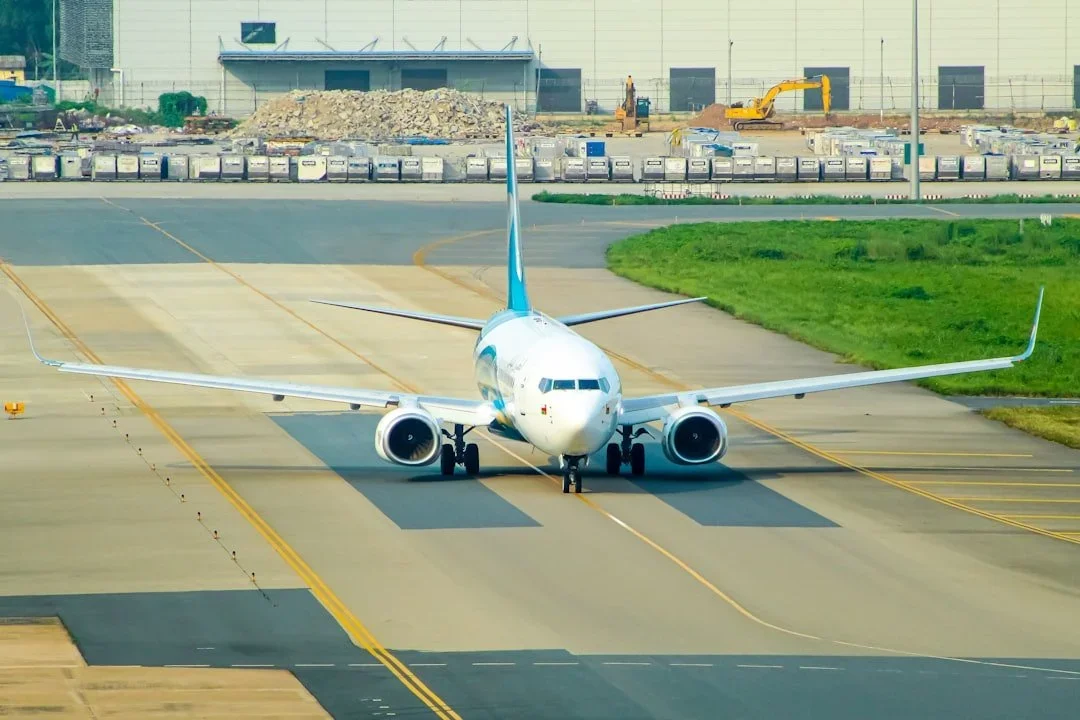 Commercial airplane on taxiway at airport with construction area in background.