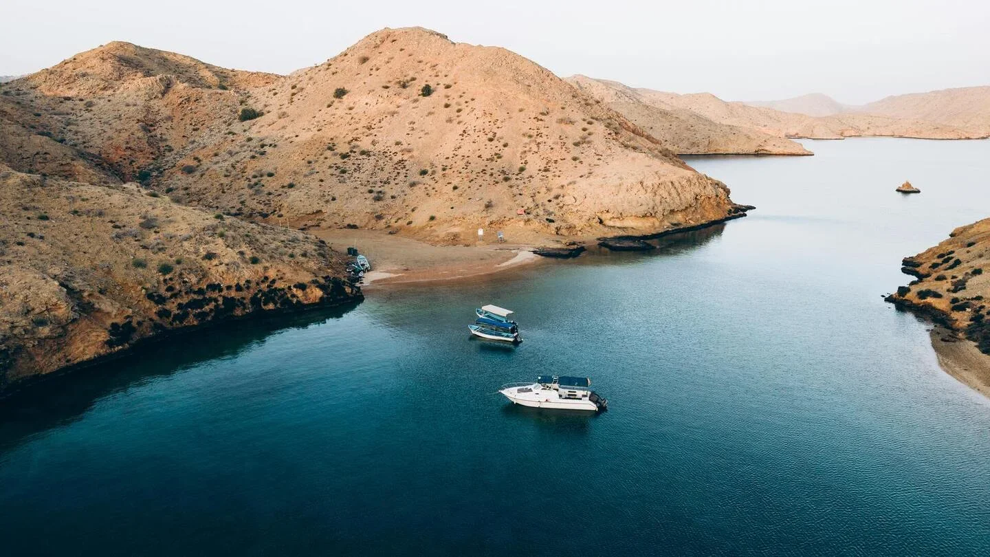 Boats anchored in a small cove with dry, rocky hills surrounding the water.