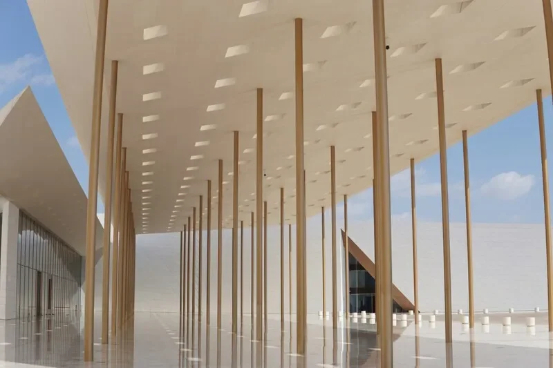 Modern building with tall vertical wooden columns supporting an overhanging roof, with a white, geometric facade and blue sky in the background.