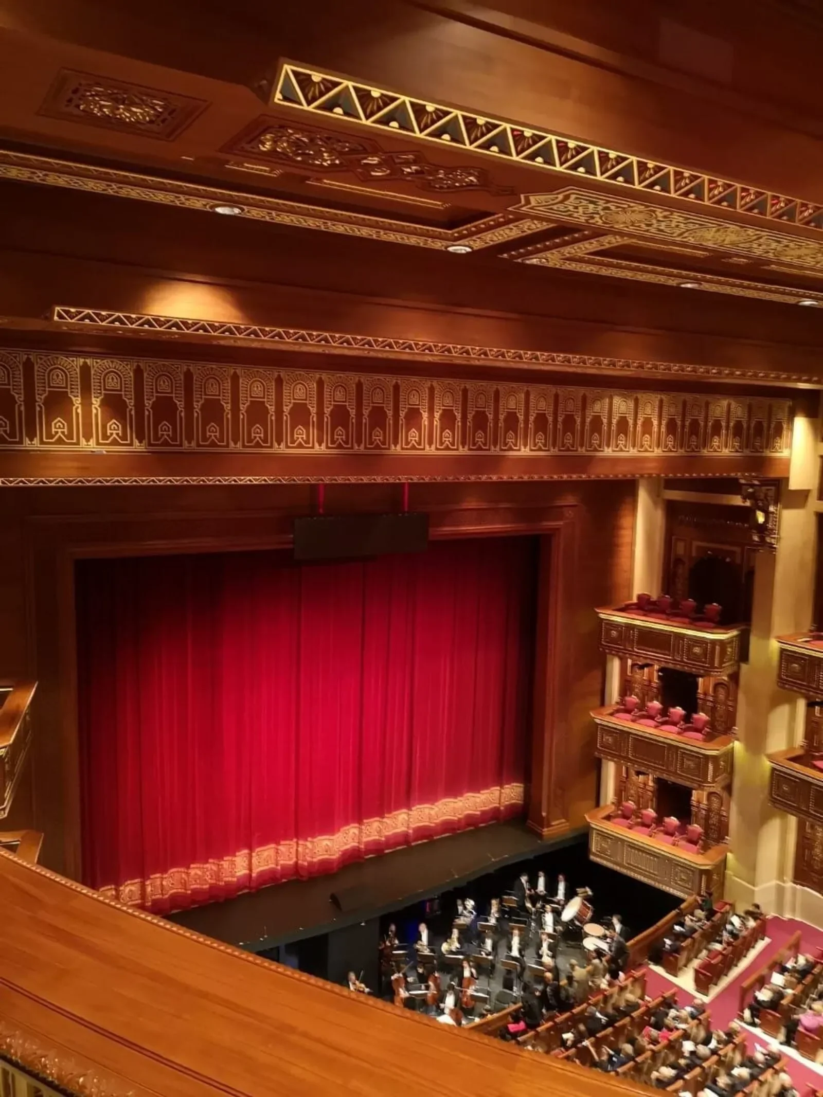 Elegant interior with grand staircase, ornate wooden arches, and intricate ceiling design in a luxurious building.