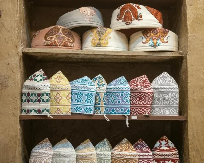 Shelves displaying traditional embroidered hats with colorful thread patterns and intricate designs, arranged in rows.