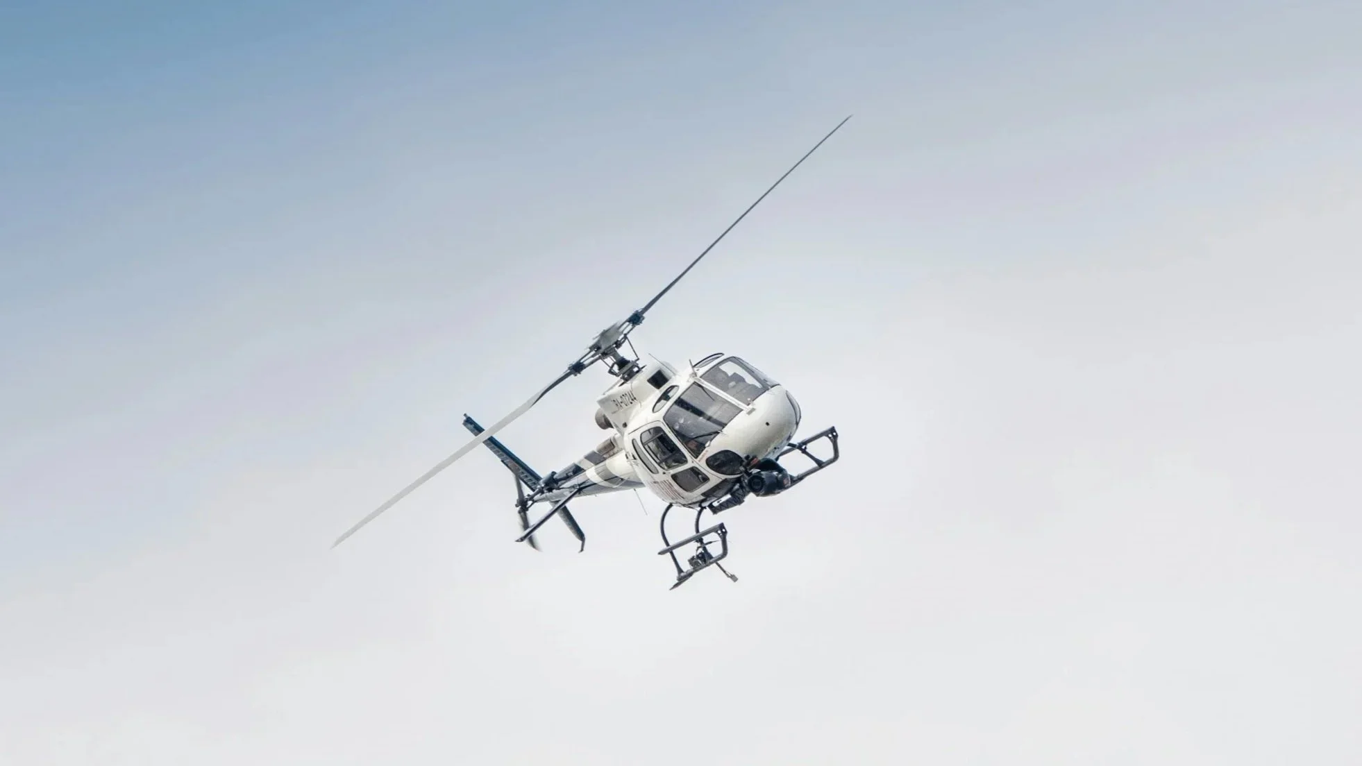 A white helicopter flying in a clear sky.