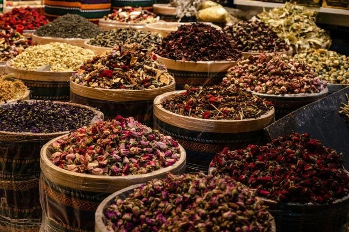 Assorted dried flowers and herbs in large woven baskets at a marketplace.
