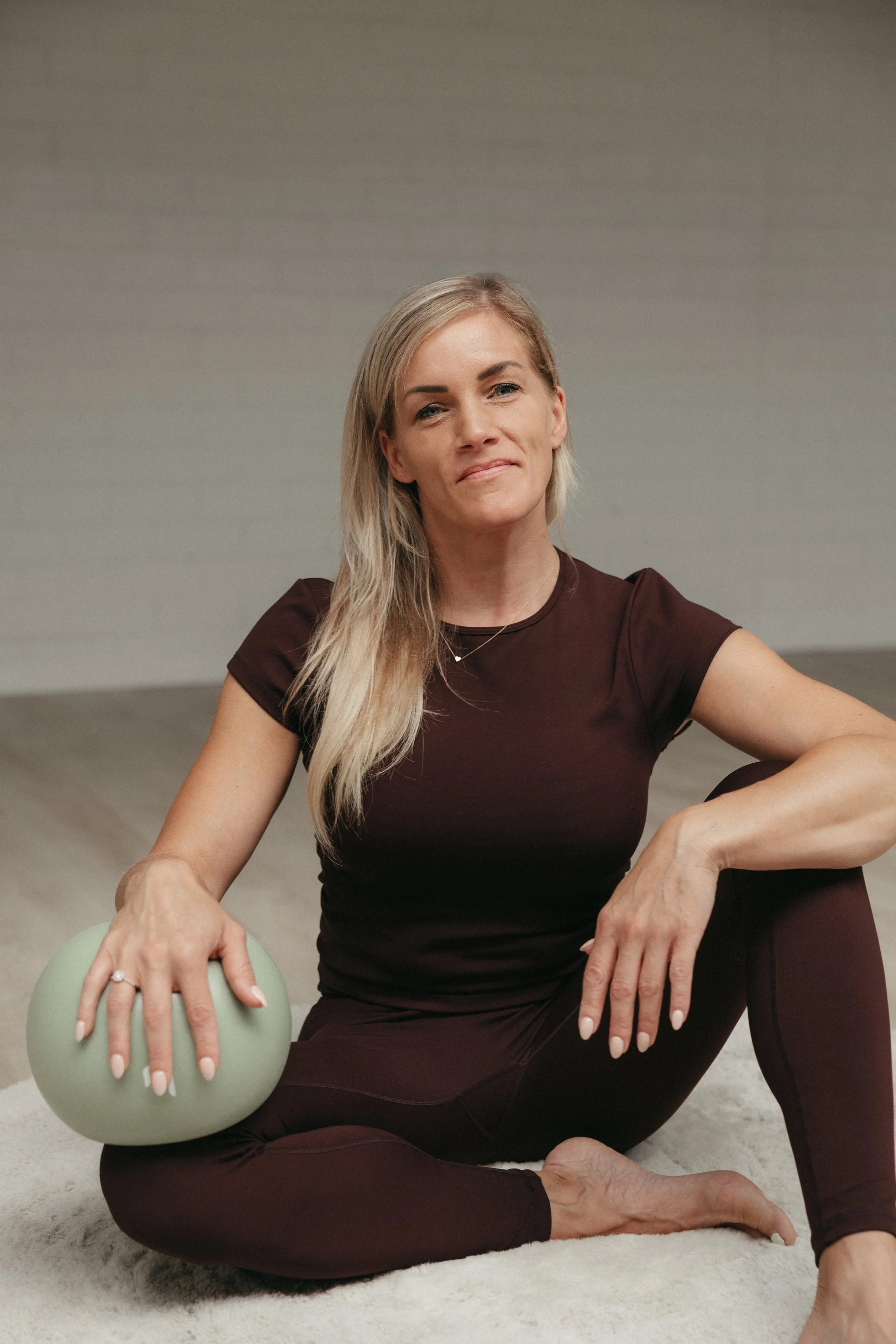 Vrouw die yoga doet op een mat met een groen gewicht in haar hand.